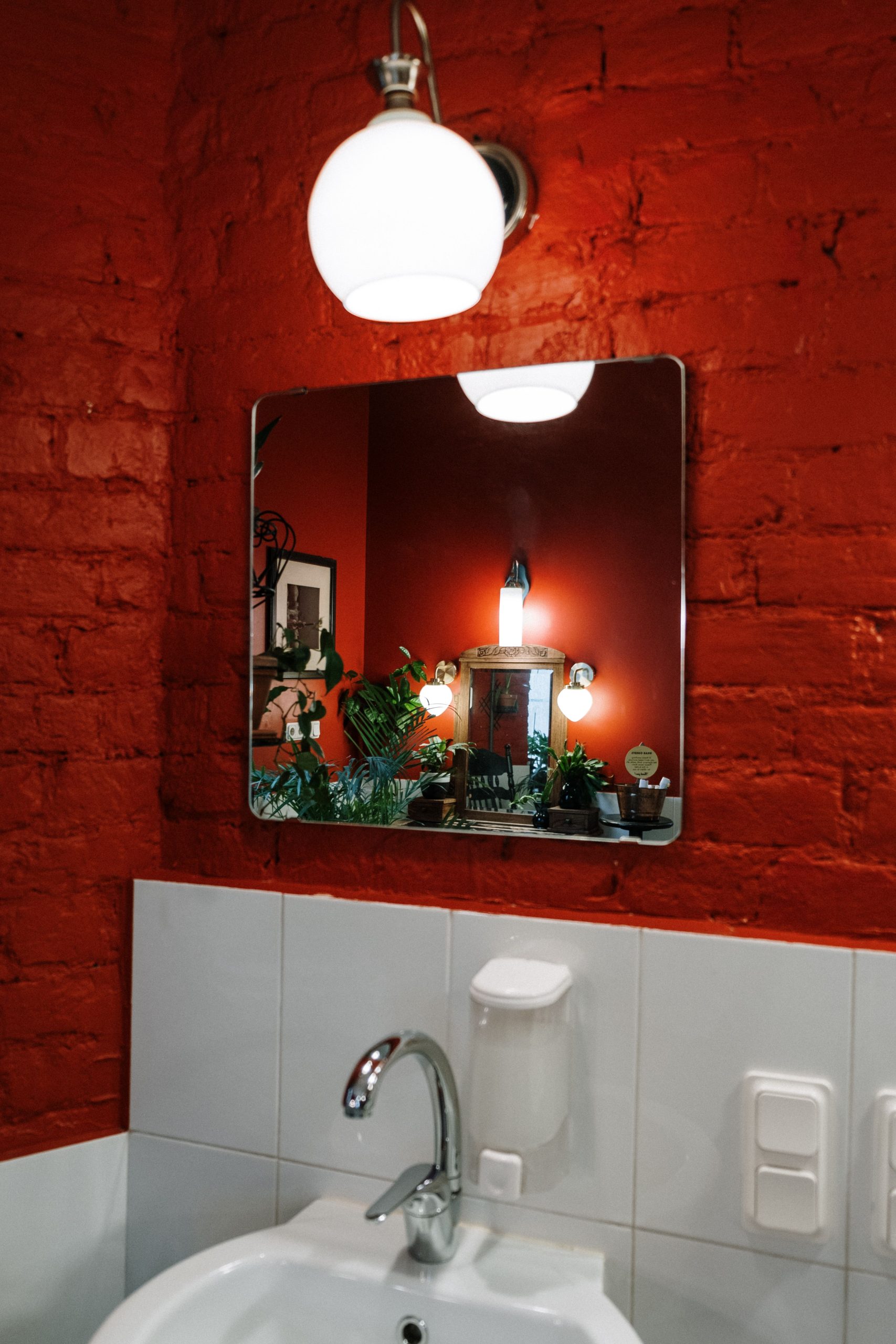 Stylish bathroom with red brick walls and plant reflections in a mirror.