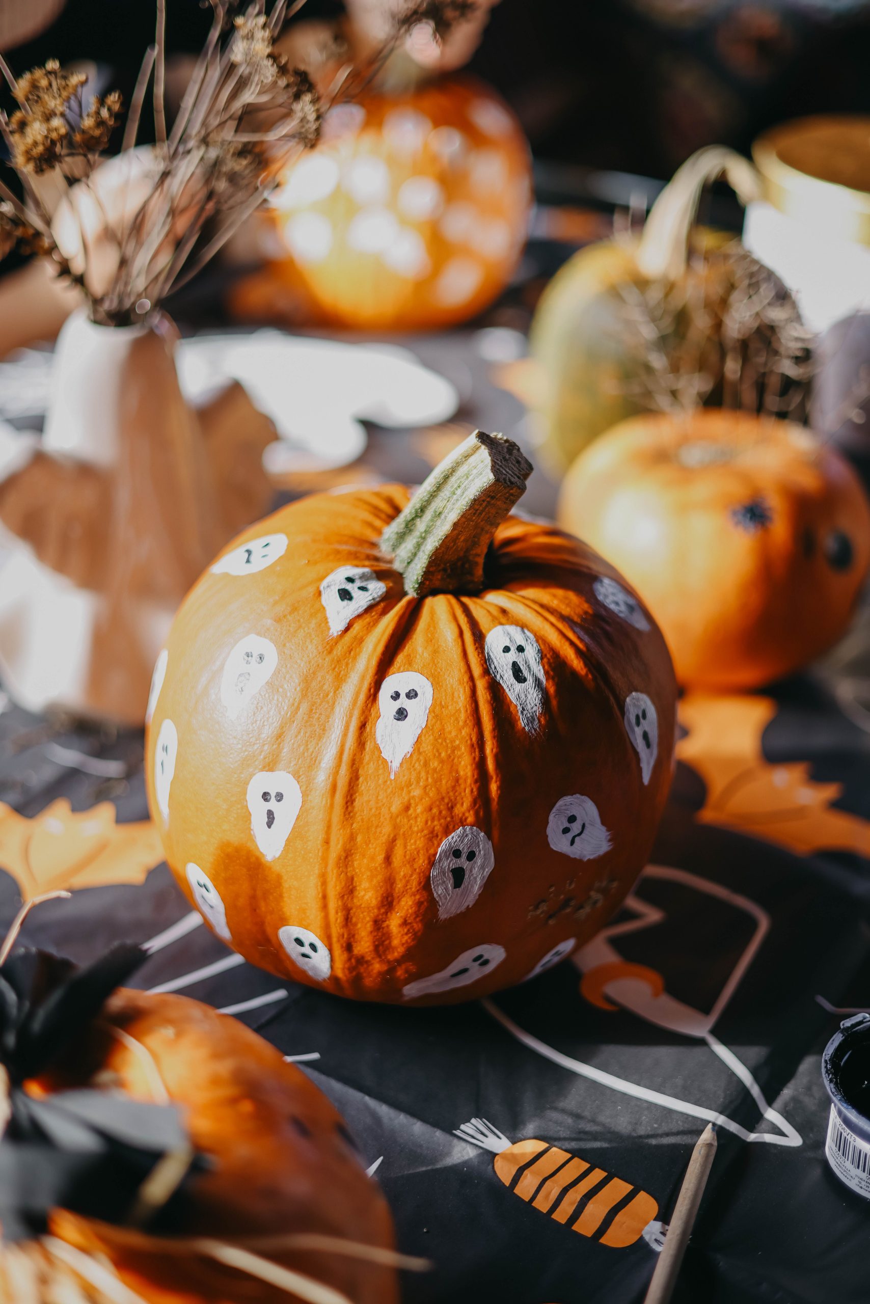 Vibrant Halloween pumpkins decorated with white ghost motifs, creating a festive autumn scene.