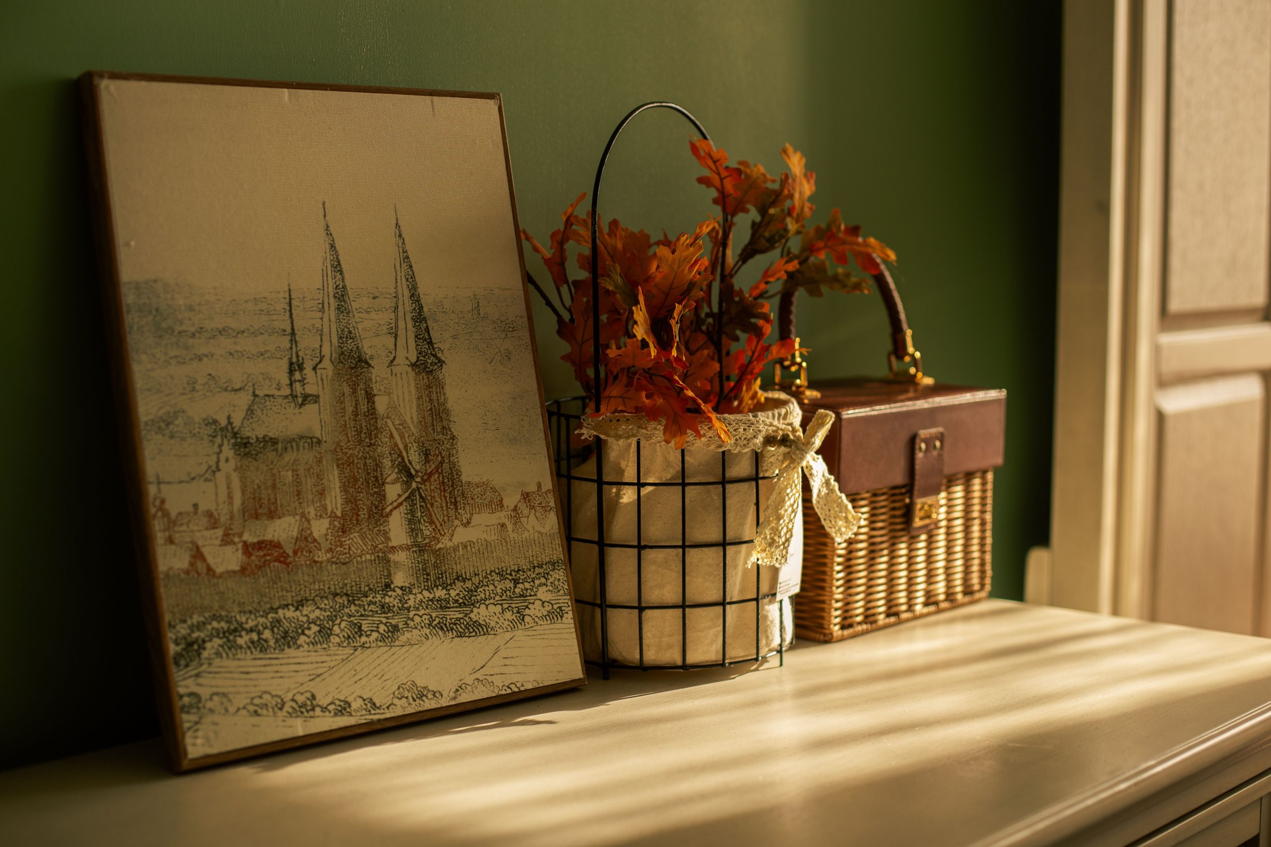 Vintage art and autumn decor on a warm-lit shelf, evoking a cozy atmosphere.