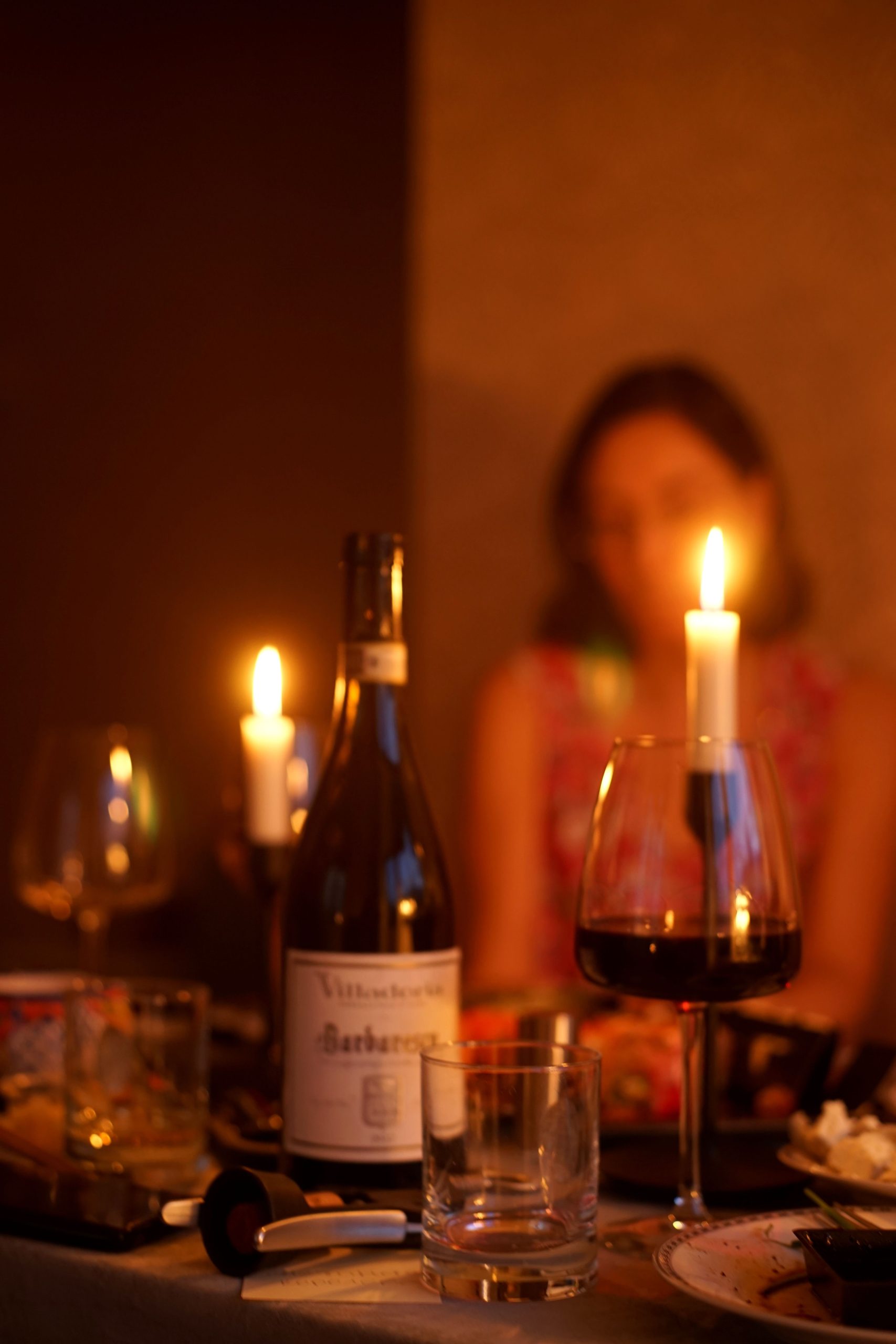 Warm and intimate candlelit dinner setting with wine and blurred background.