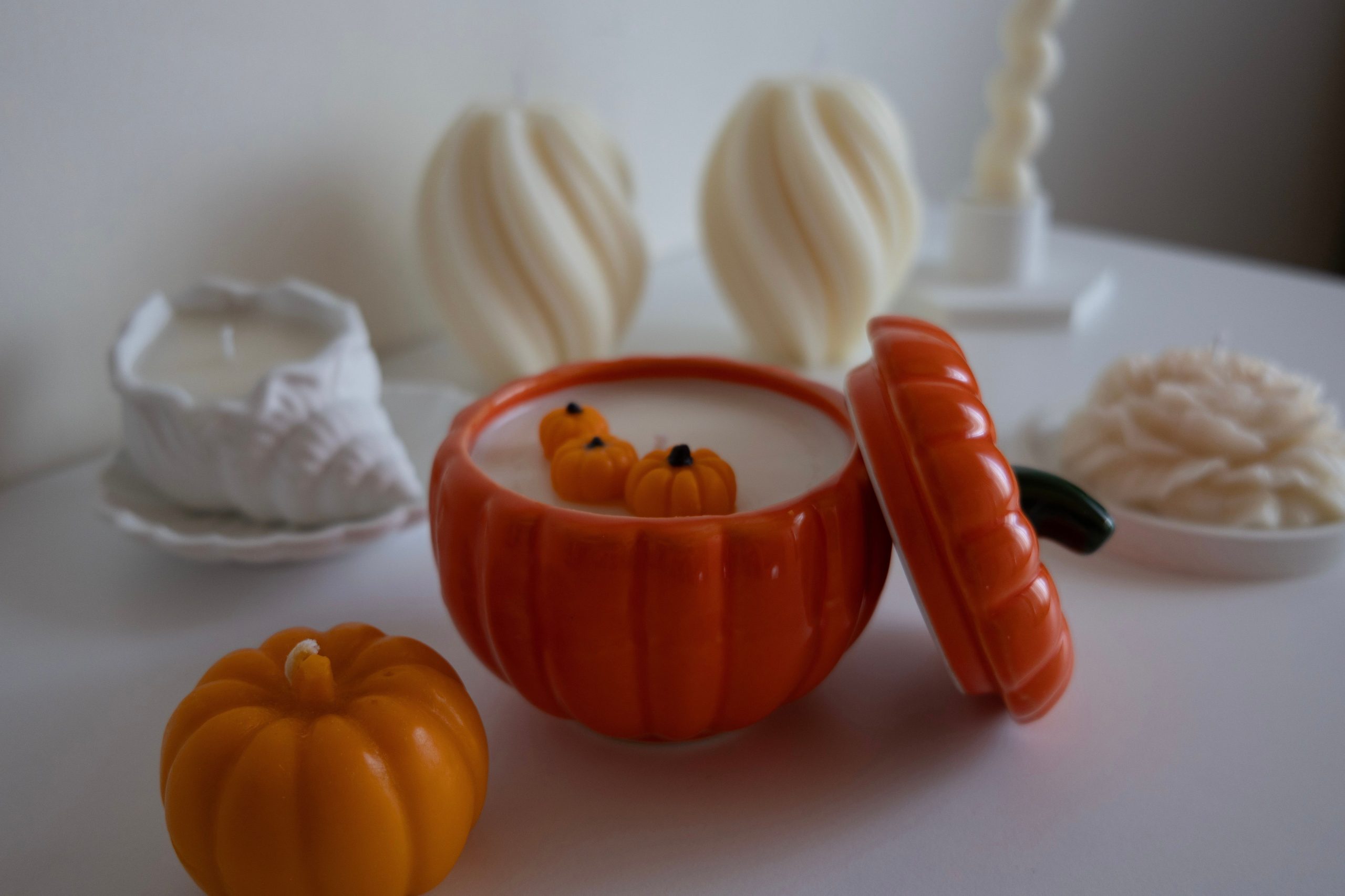 Warm and inviting autumn decor featuring pumpkin-shaped candles on a white desk.