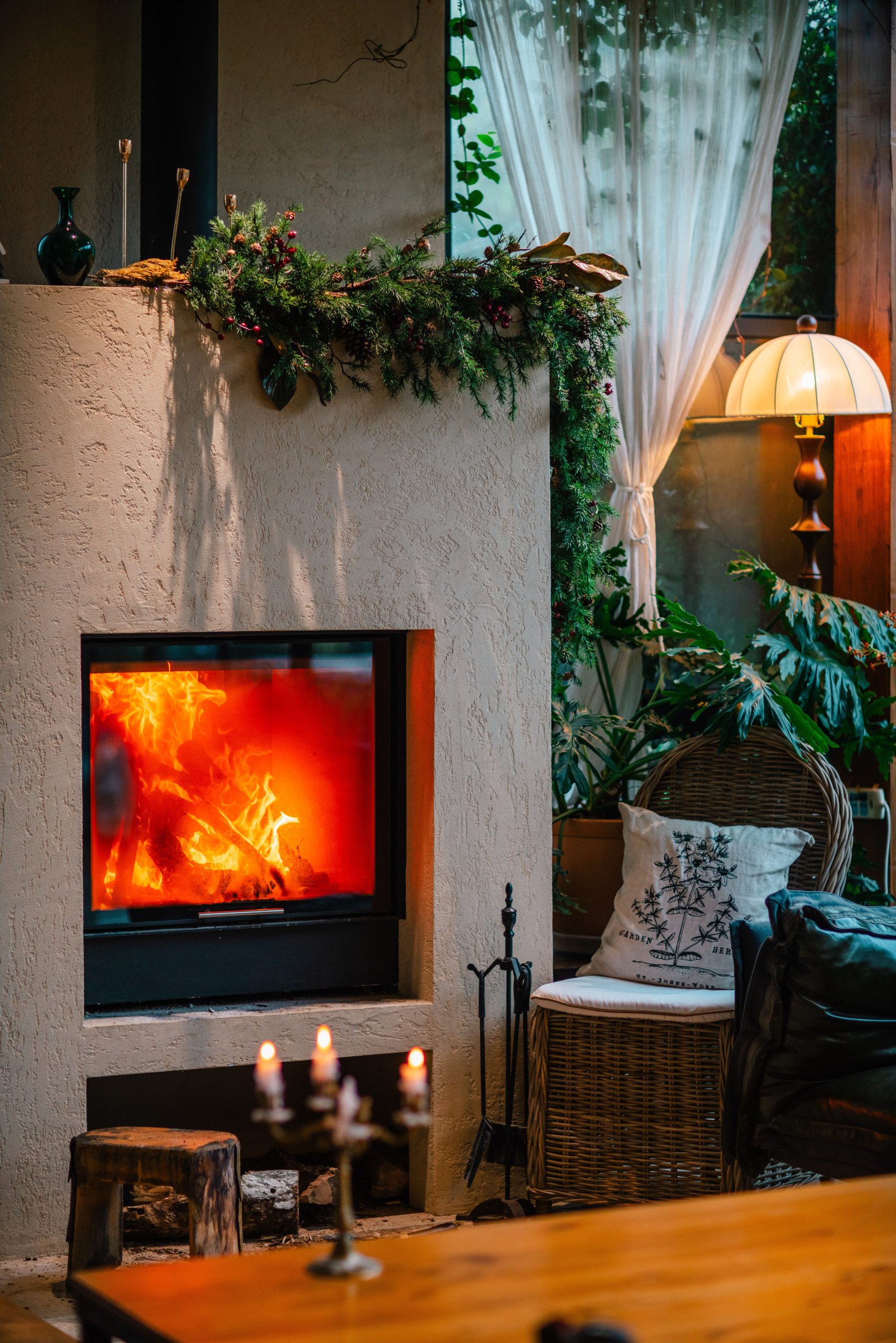 Warm and inviting living room with a fireplace, candles, and lush greenery.