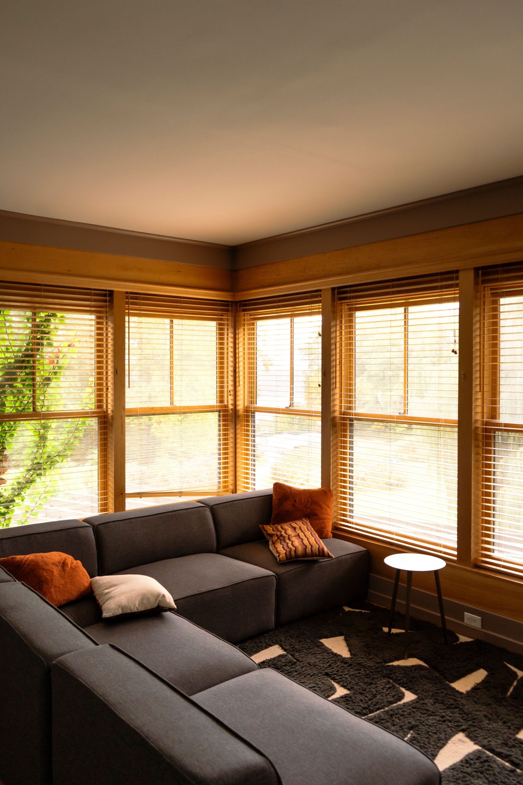 Warm and inviting living room with large windows showcasing autumn foliage.