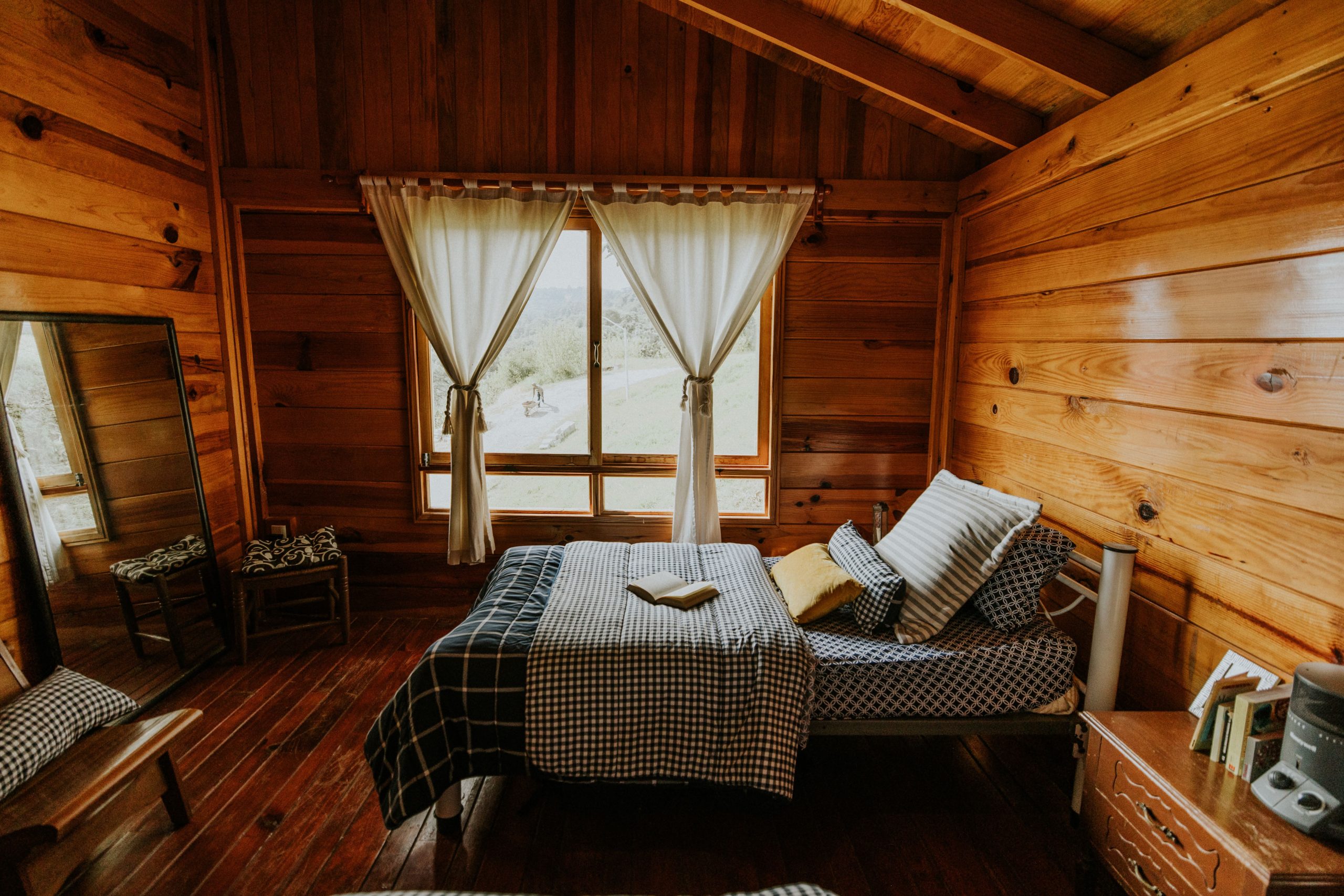 Warm and inviting wooden cabin bedroom featuring a scenic outdoor view with natural light.