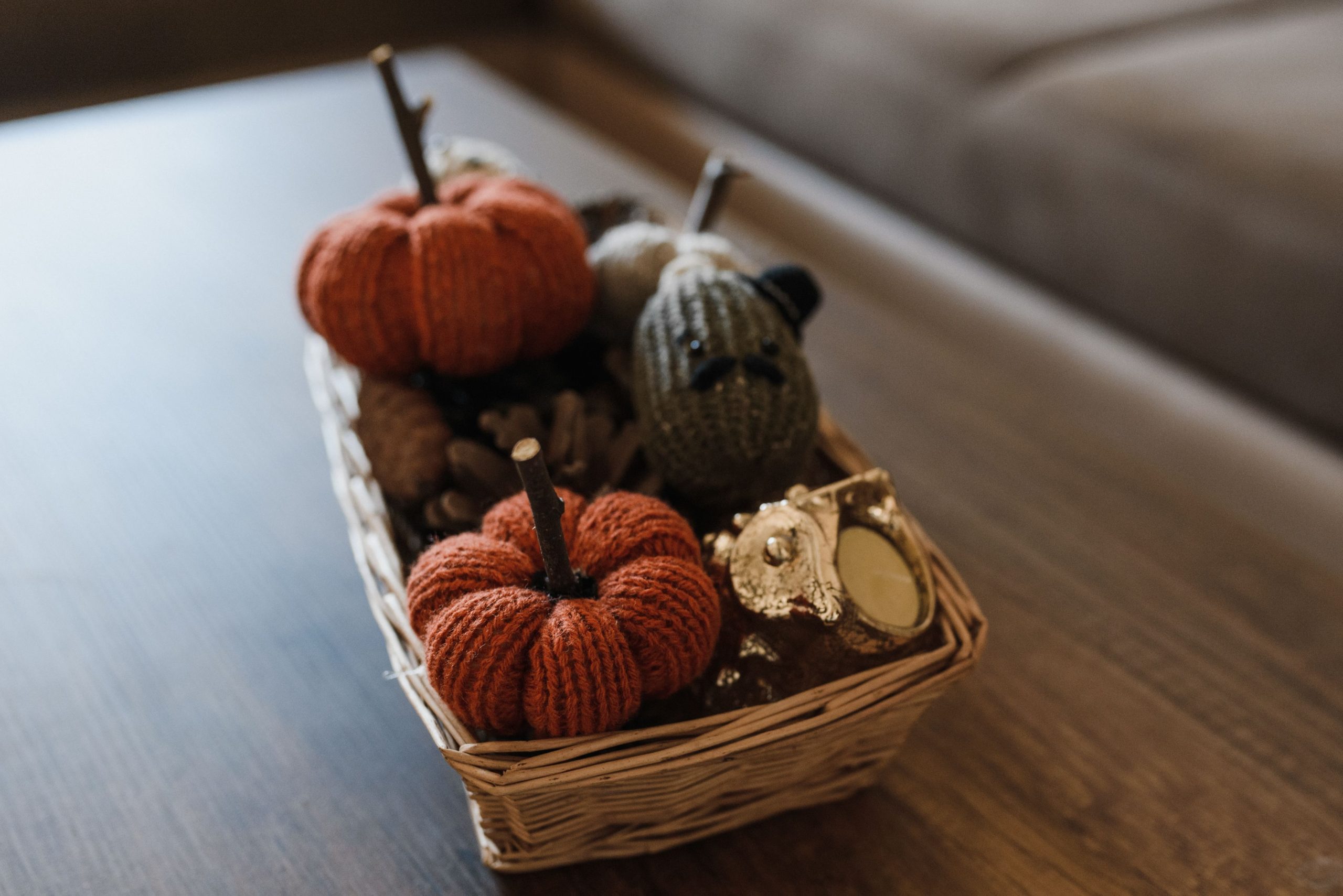 Warm autumn decorations featuring knitted pumpkins in a wicker basket.