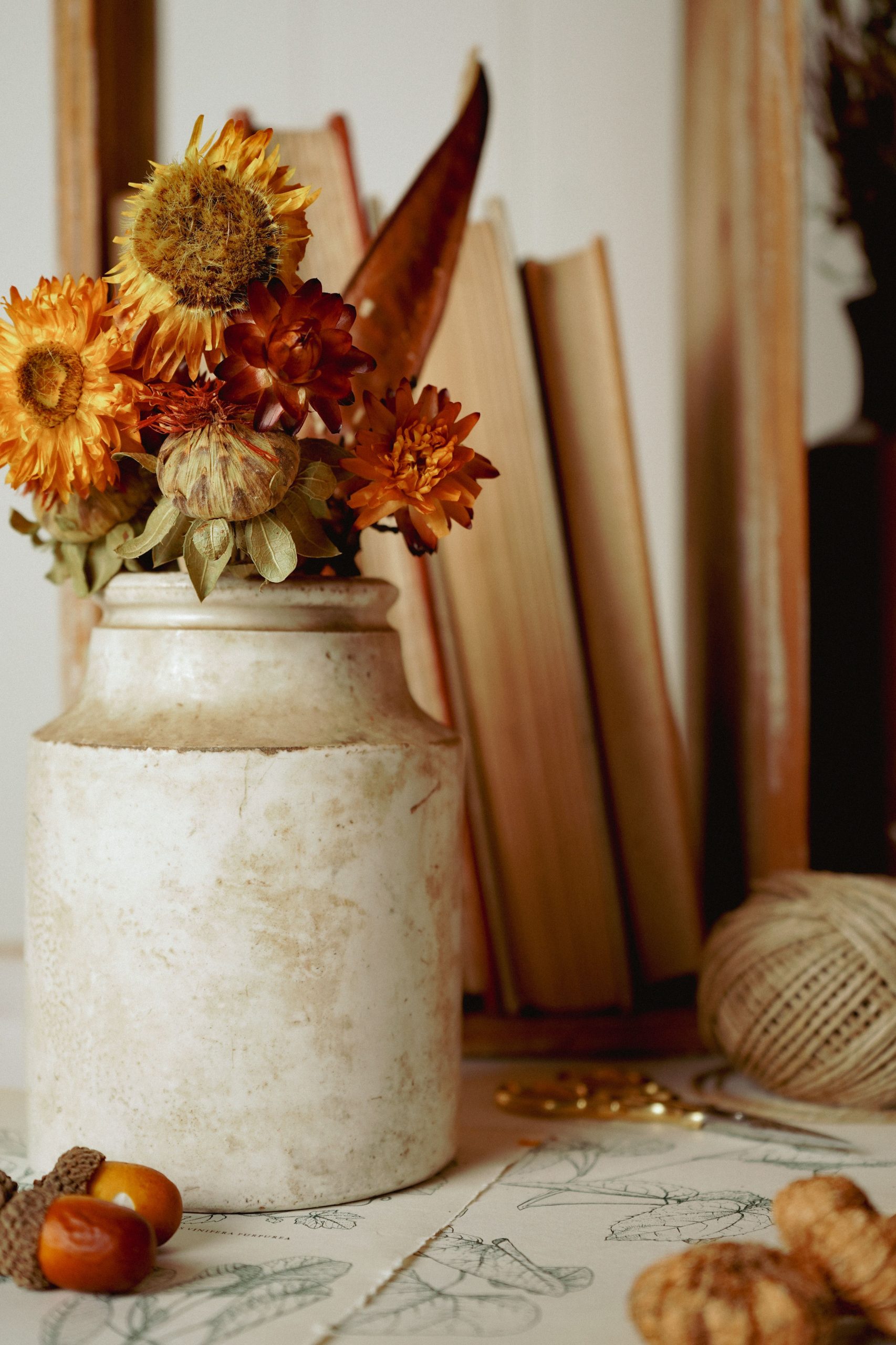 Warm autumn still life featuring dried flowers, vintage books, and cozy decor.
