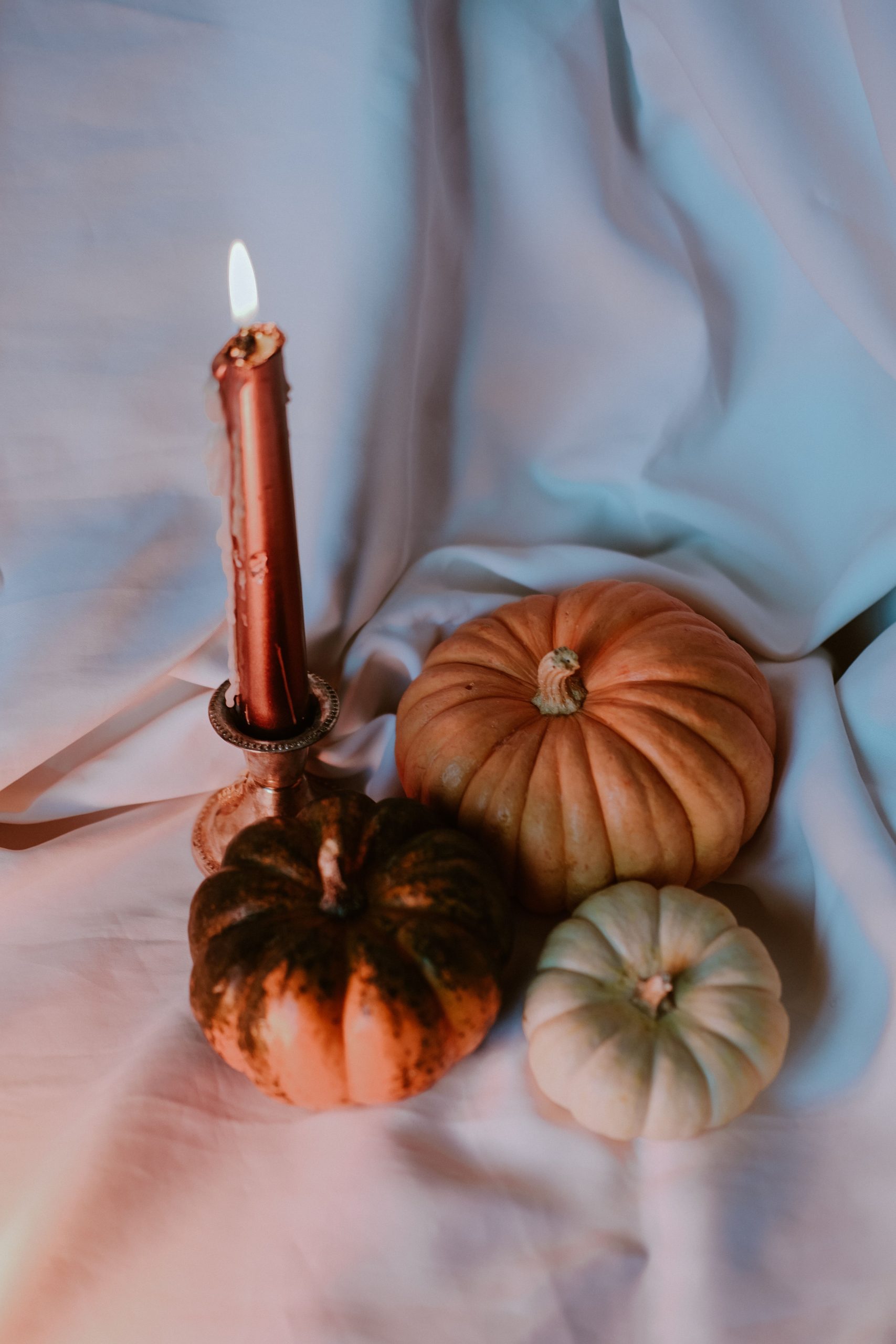 Warm autumn still life featuring pumpkins and a candle, perfect for seasonal themes like Halloween or Thanksgiving.