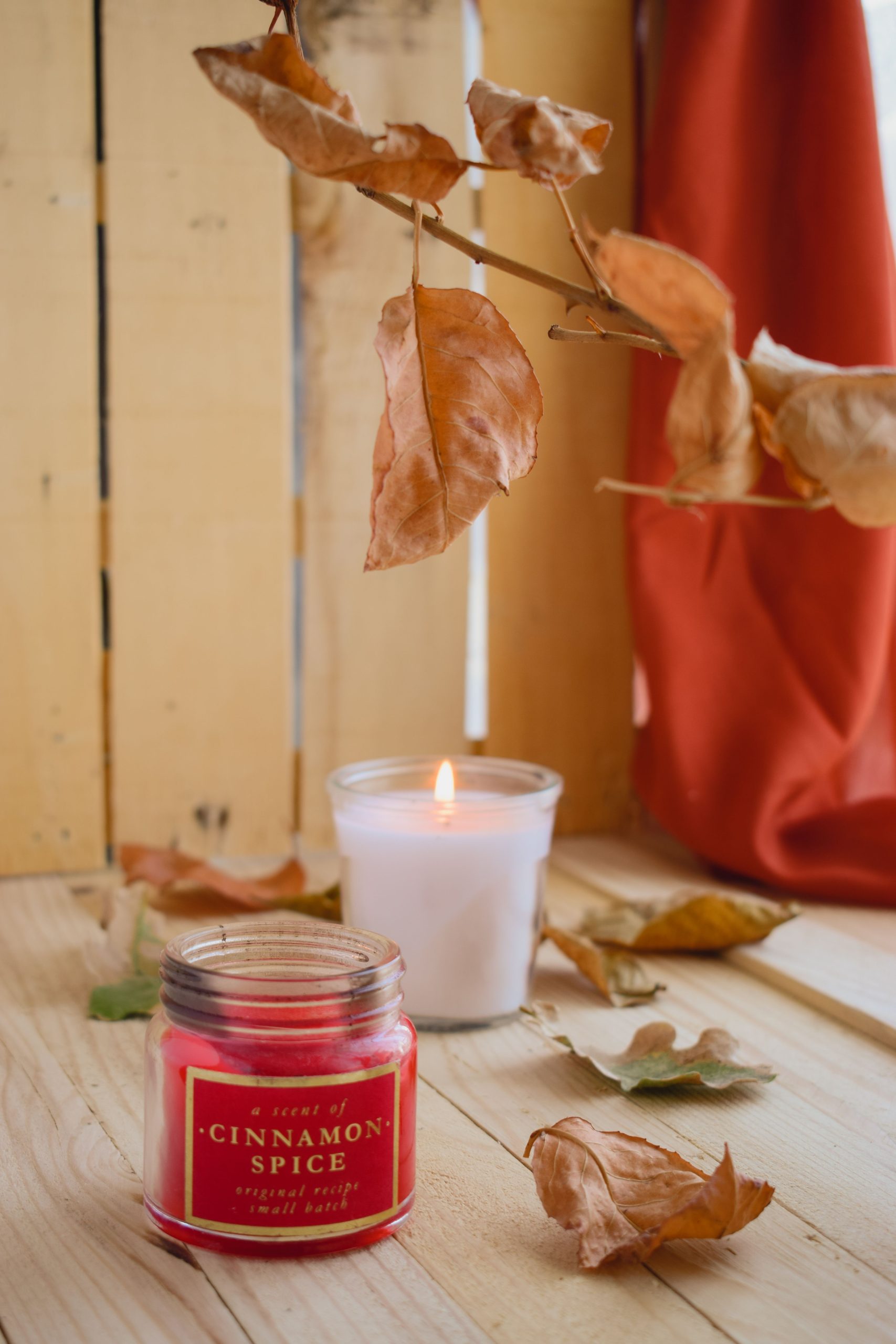 Warm fall ambiance featuring cinnamon spice candles and autumn leaves indoors.