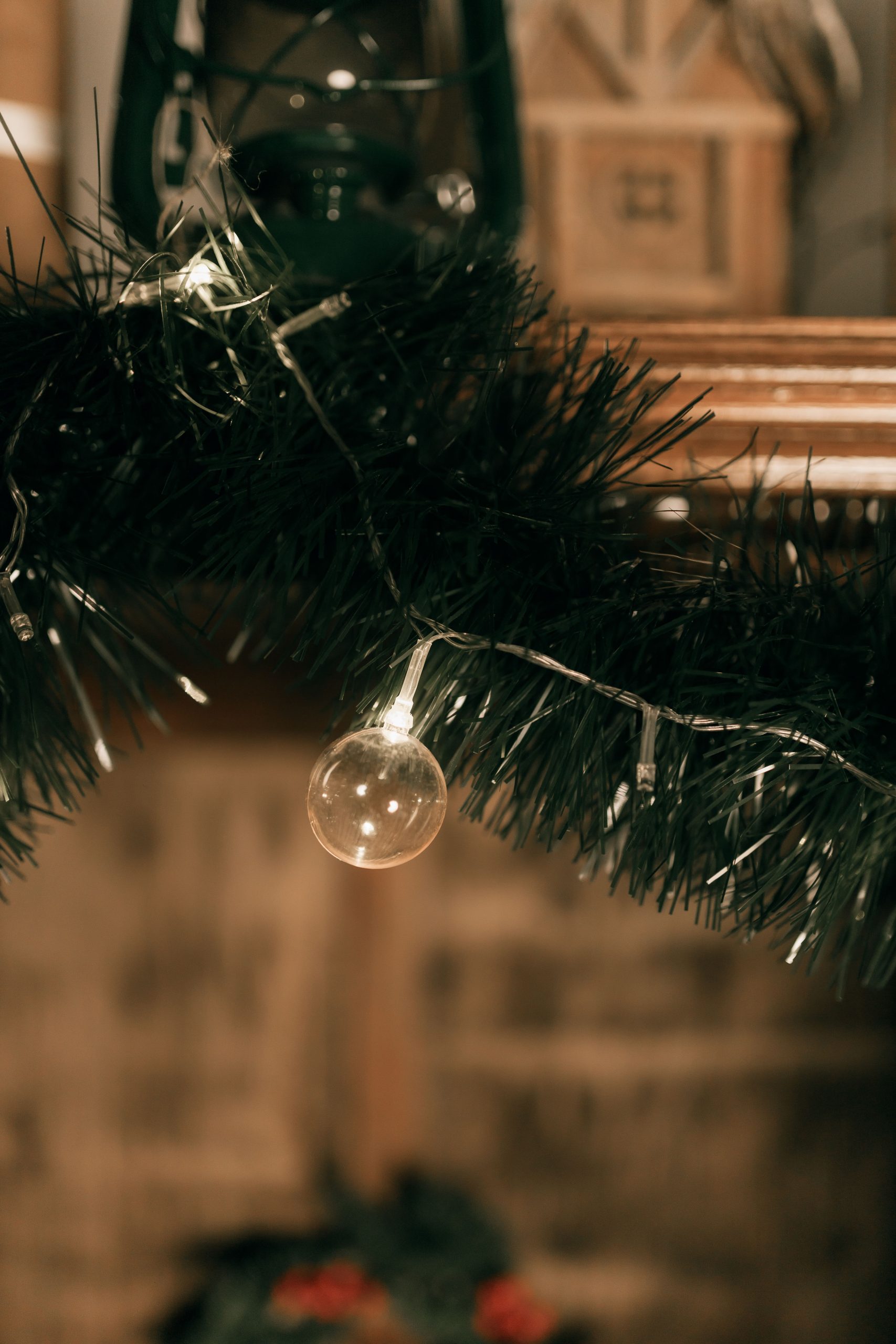 Warm holiday scene featuring a garland with string lights and festive ornaments.
