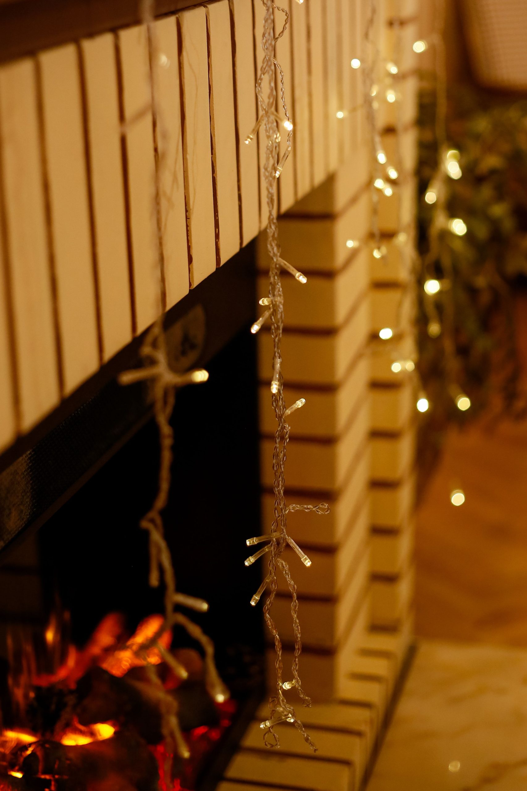 Warm indoor fireplace decorated with glowing string lights, creating a festive atmosphere.