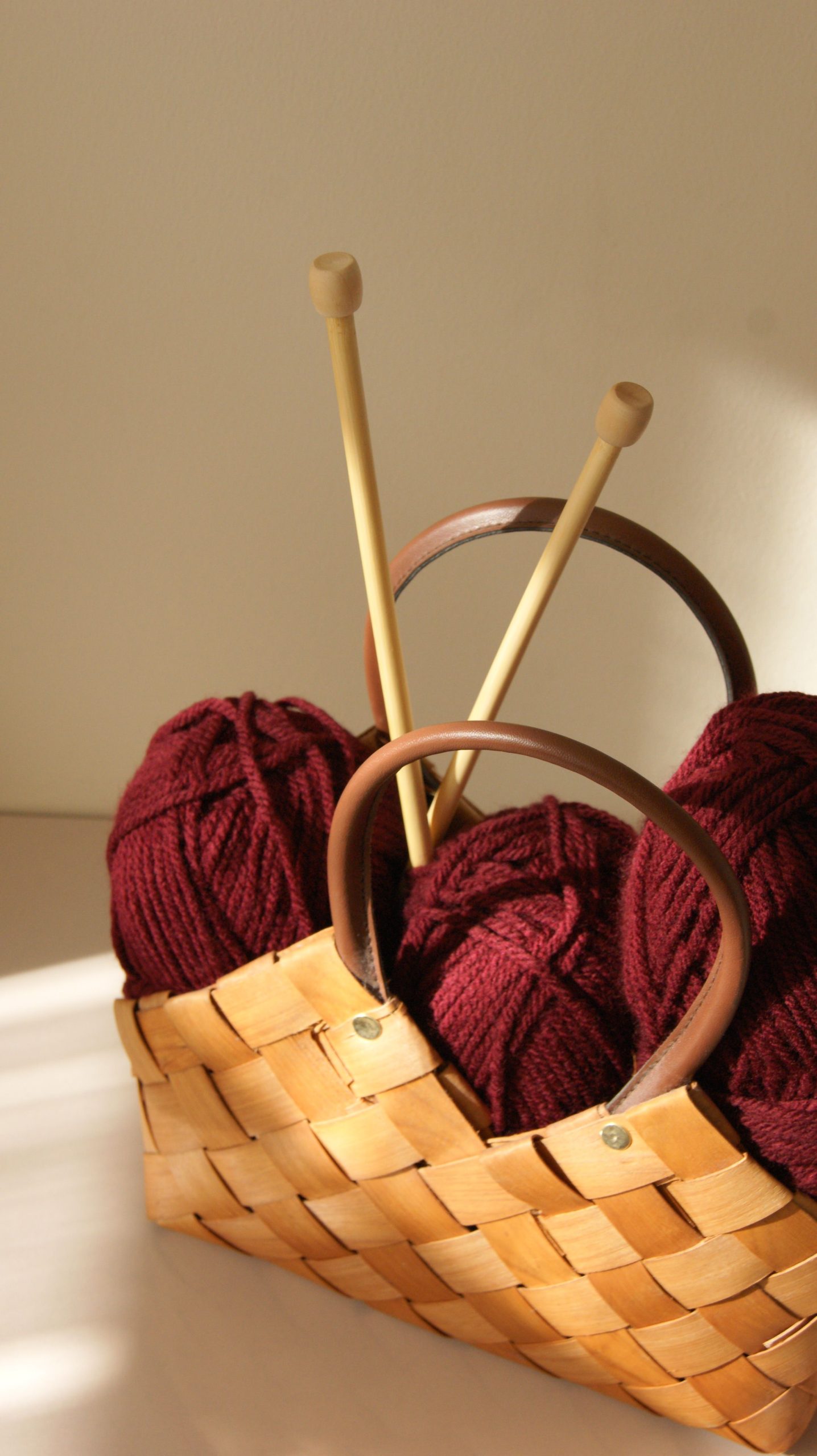 Warm sunlight on yarn and needles in a rustic basket, ideal for cozy craft themes.