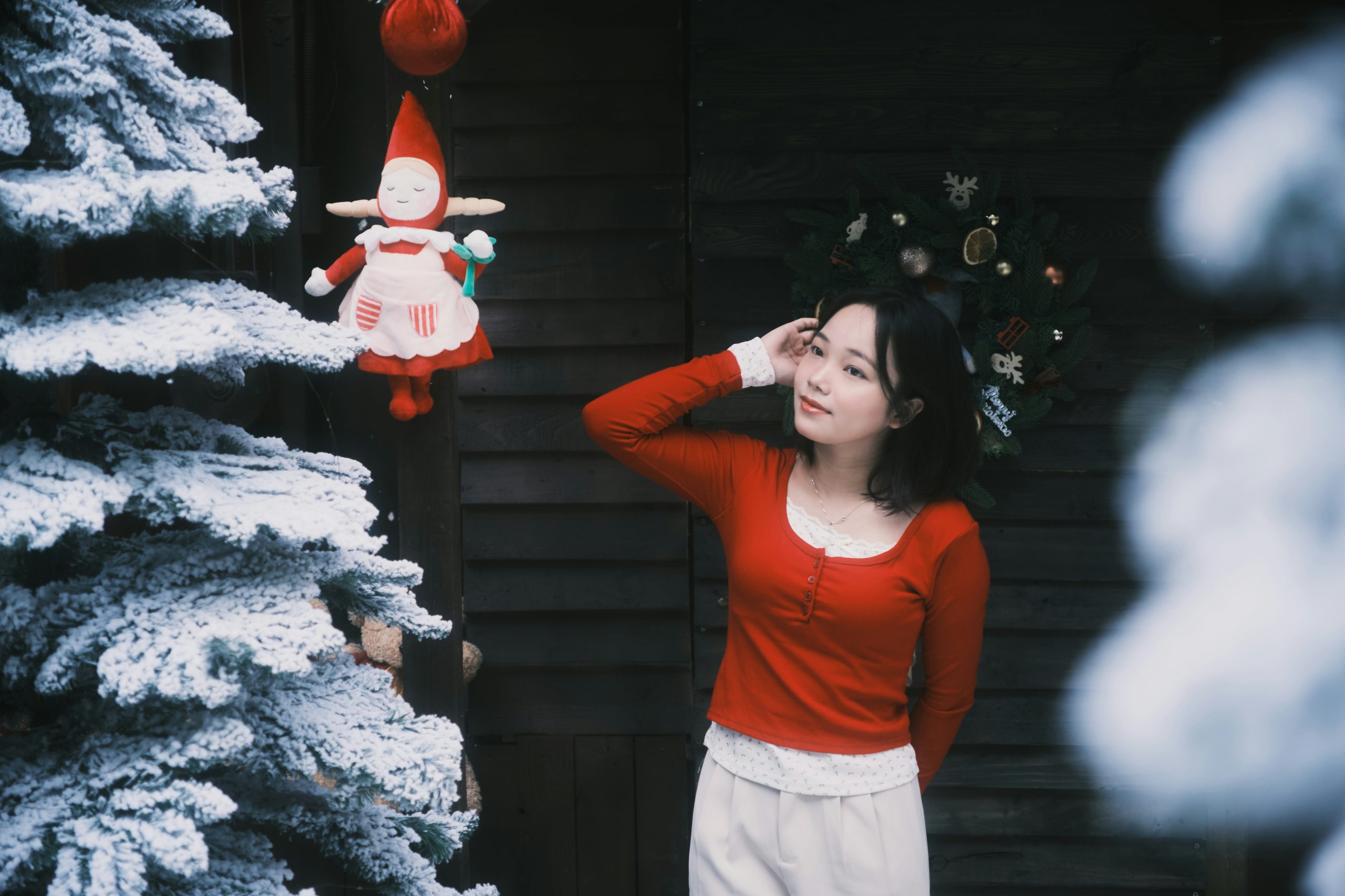 Woman in red sweater by snowy christmas tree