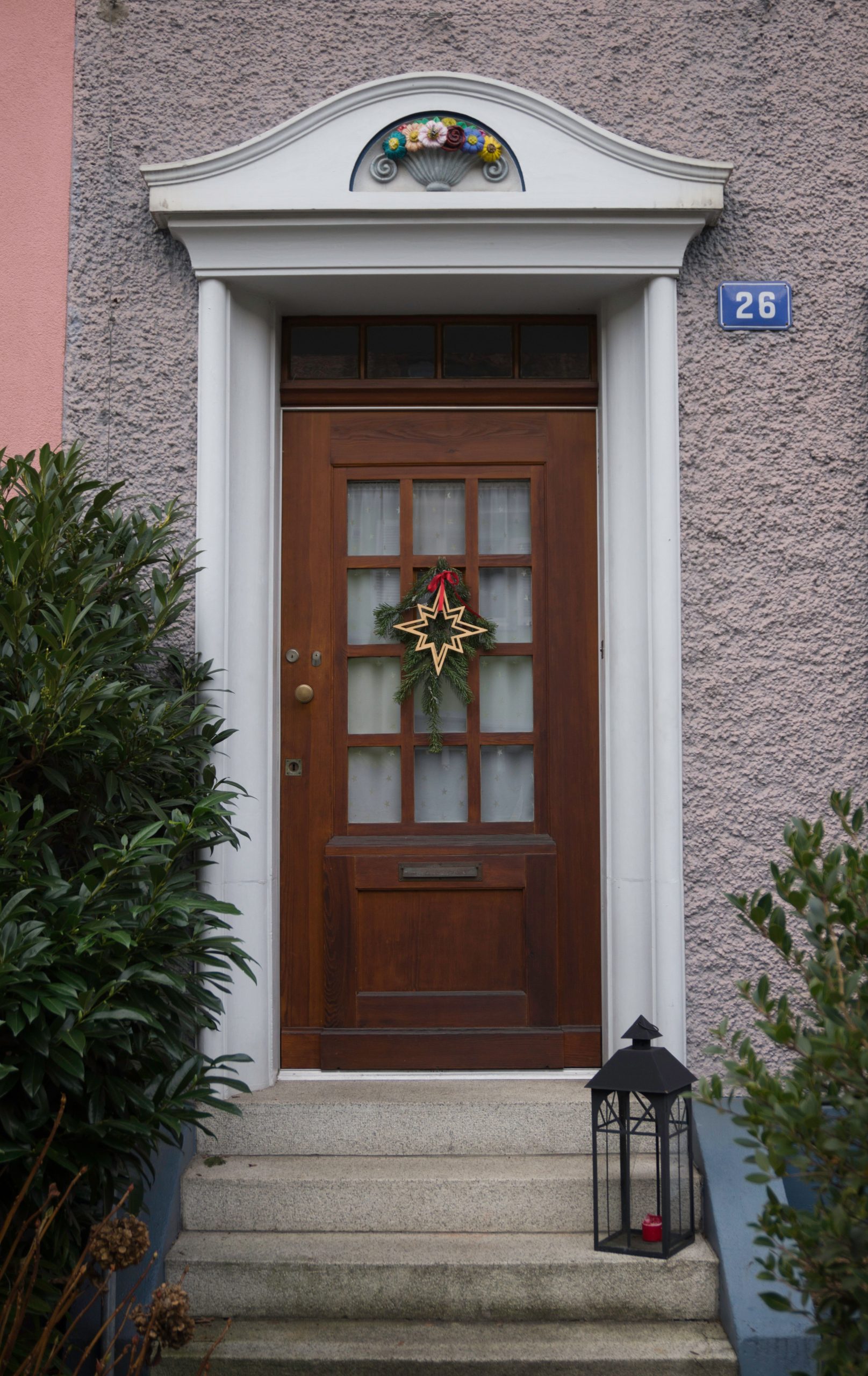 Wooden door with festive wreath and star decoration, house number 26