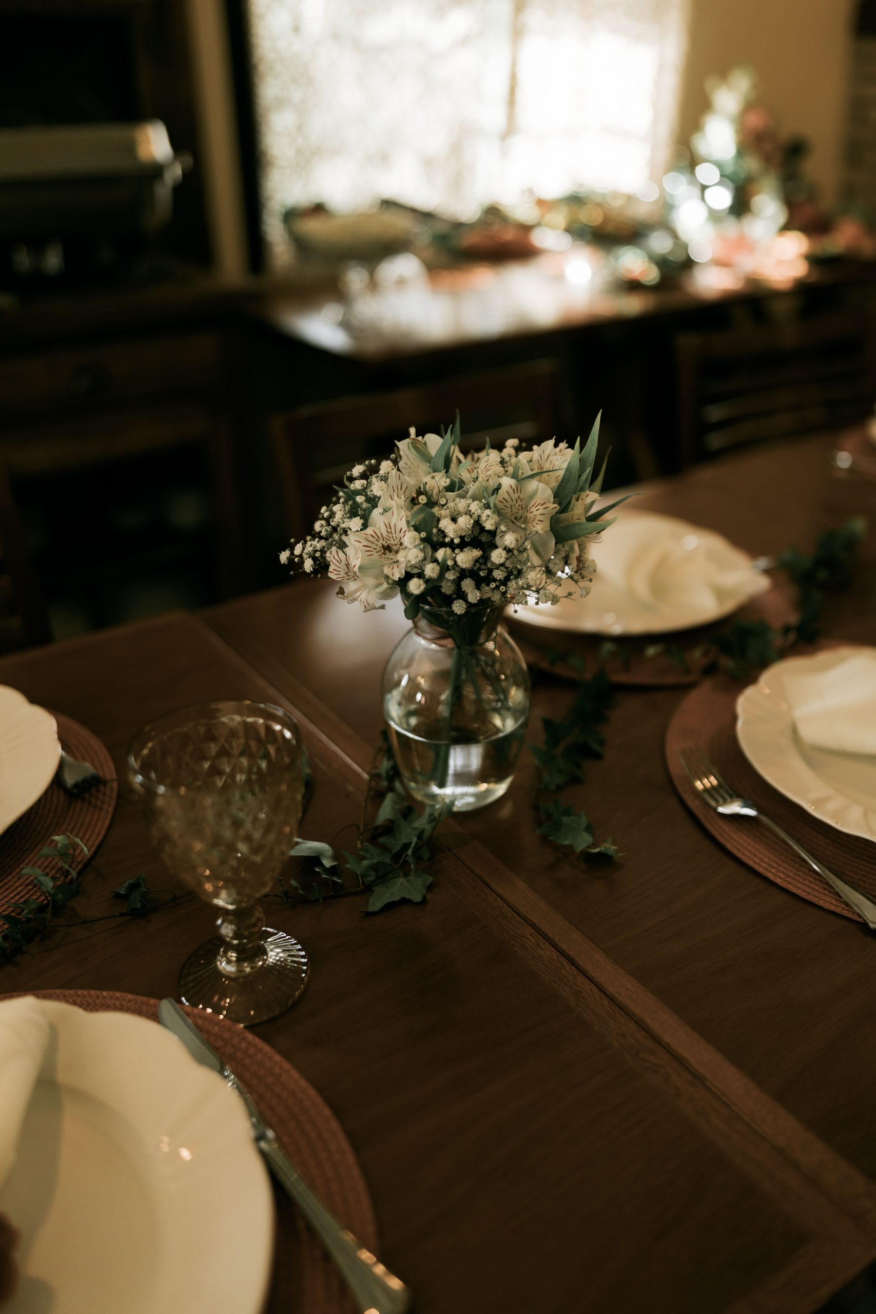 A beautifully arranged dining table with floral centerpiece and fine tableware, creating a cozy atmosphere.