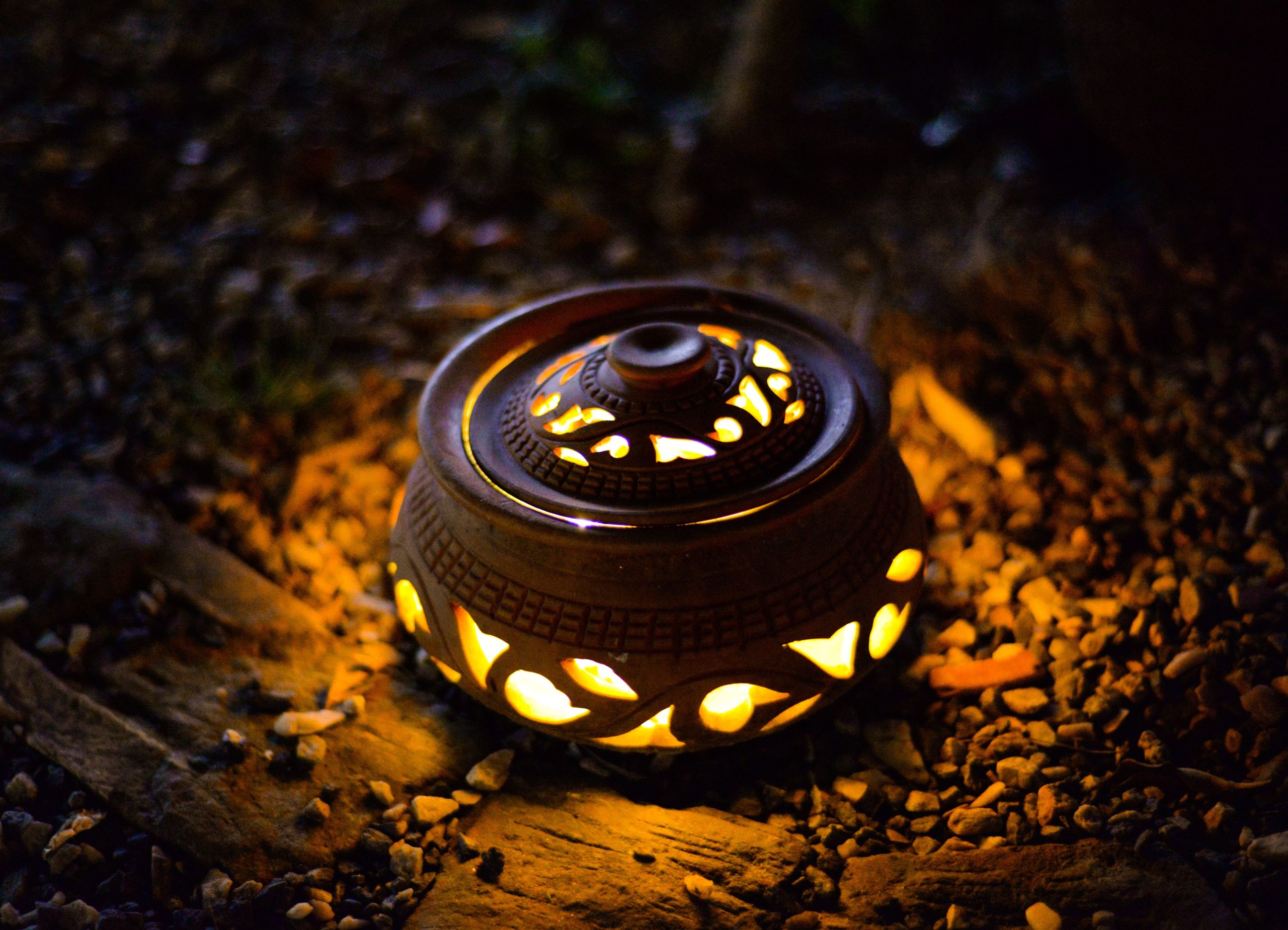 A beautifully crafted clay lantern illuminates a garden path with intricate light patterns.