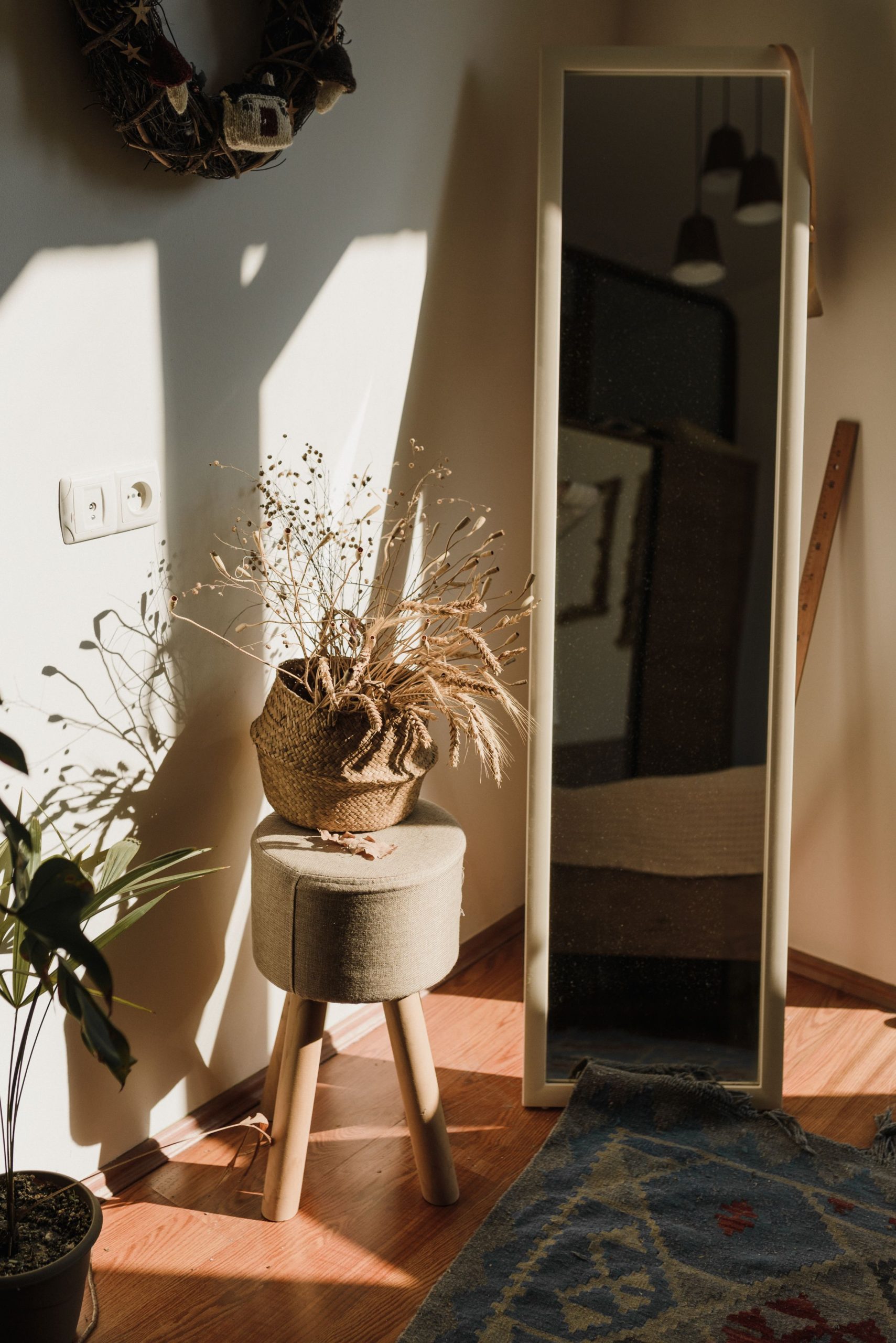 A cozy room with dried plants and a mirror reflecting warm natural light.