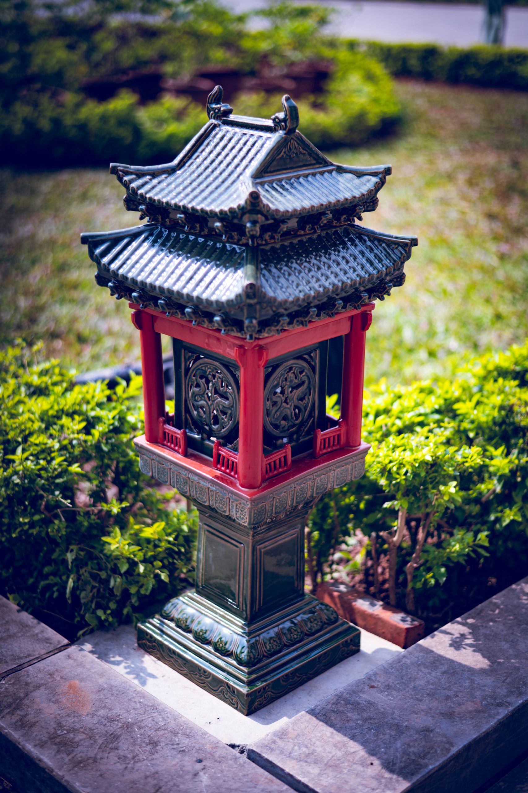 A decorative Asian-style lantern surrounded by lush greenery in a garden.
