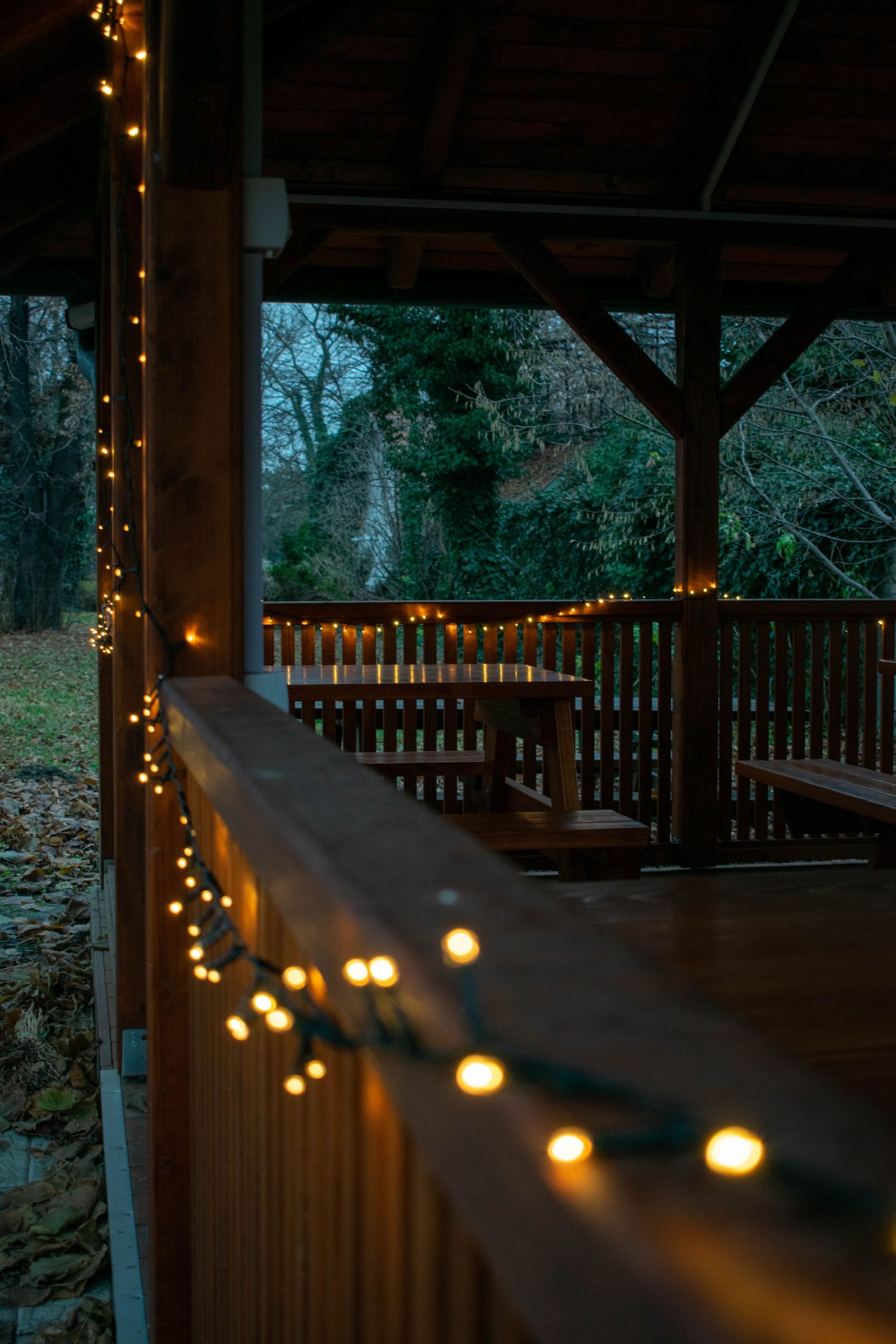 A gazebo illuminated with warm string lights at dusk, creating a cozy outdoor ambiance.