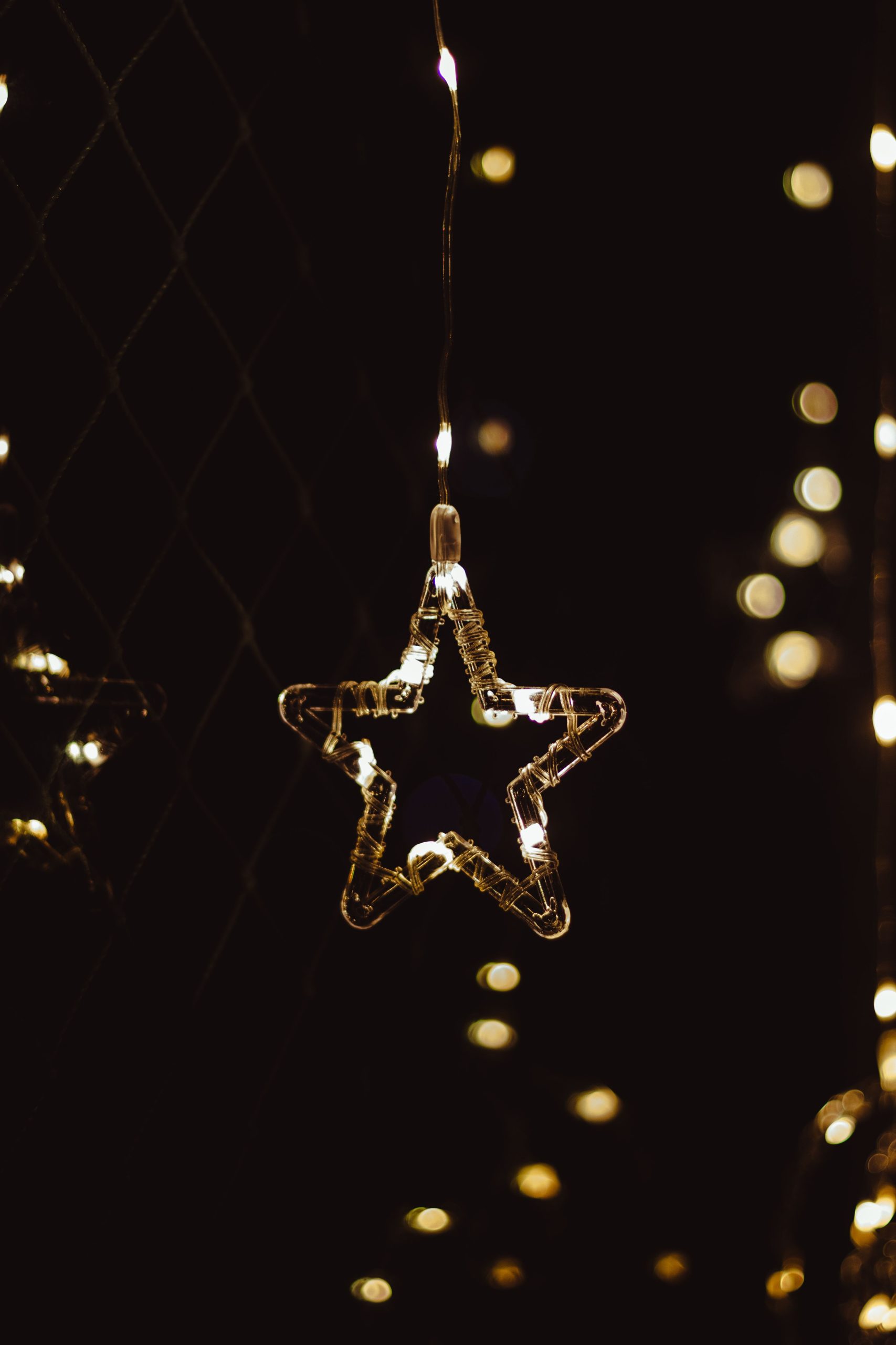 A glowing star-shaped string light hanging in the dark, creating a cozy ambiance.