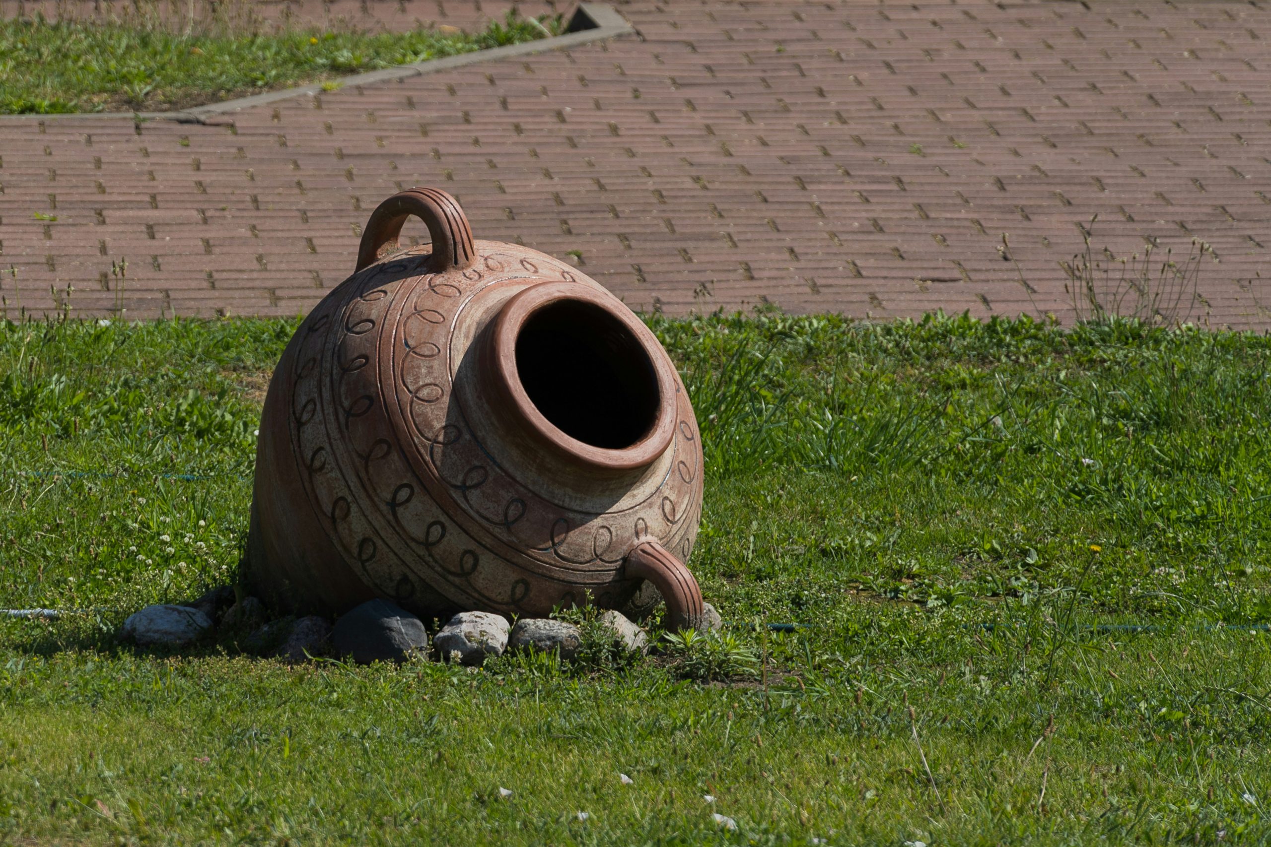 a large vase sitting on top of a lush green field
