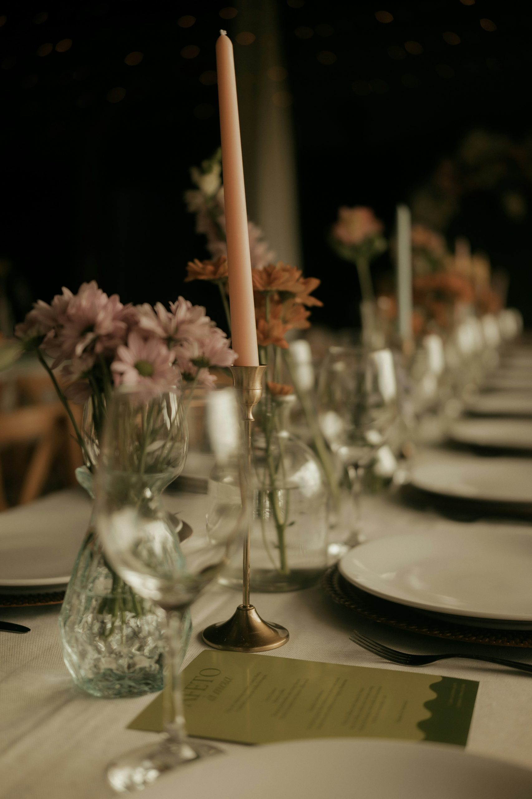 A long dining table set with plates, glasses, and candles