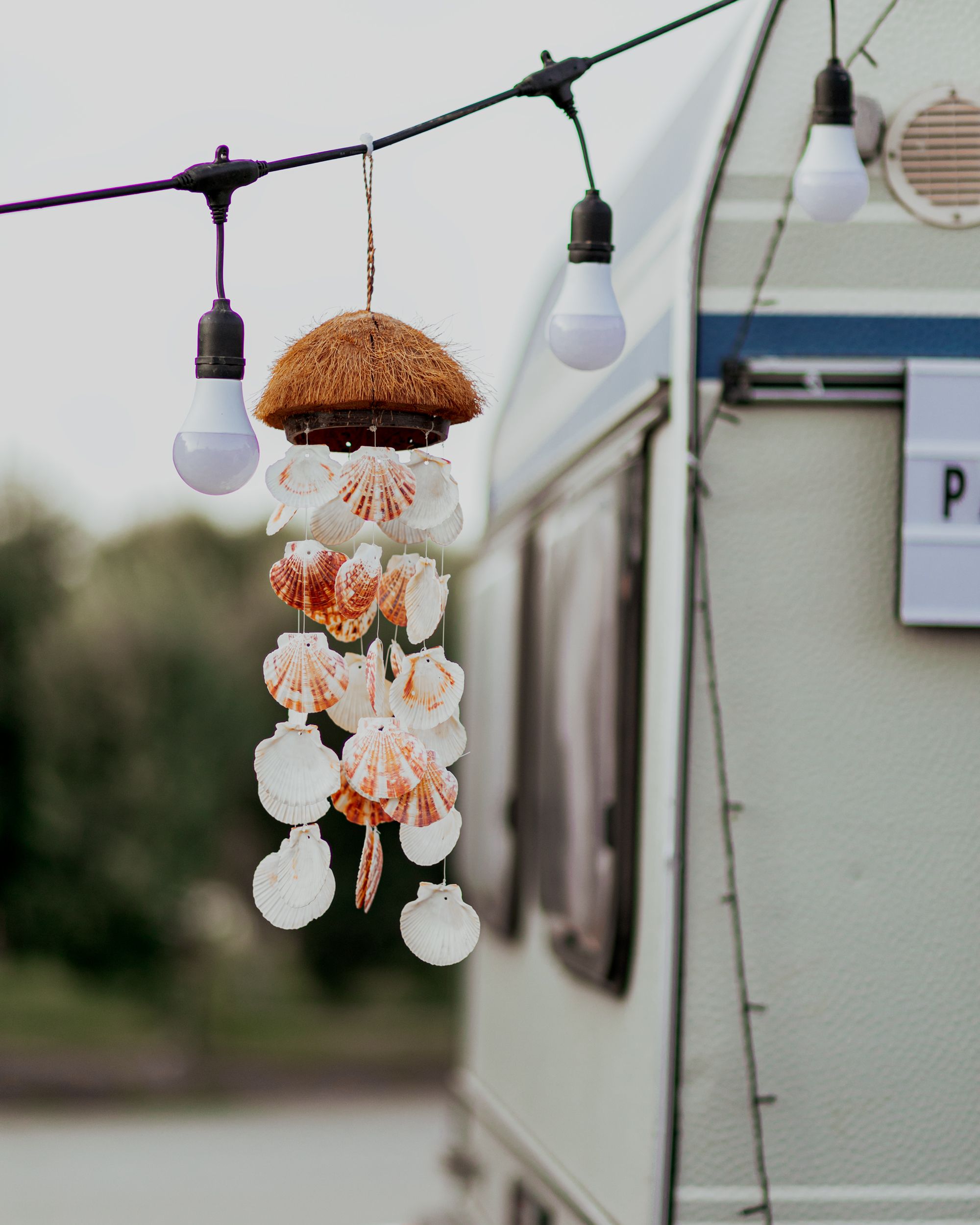 A seashell wind chime hanging on a caravan decorated with light bulbs in Baku.