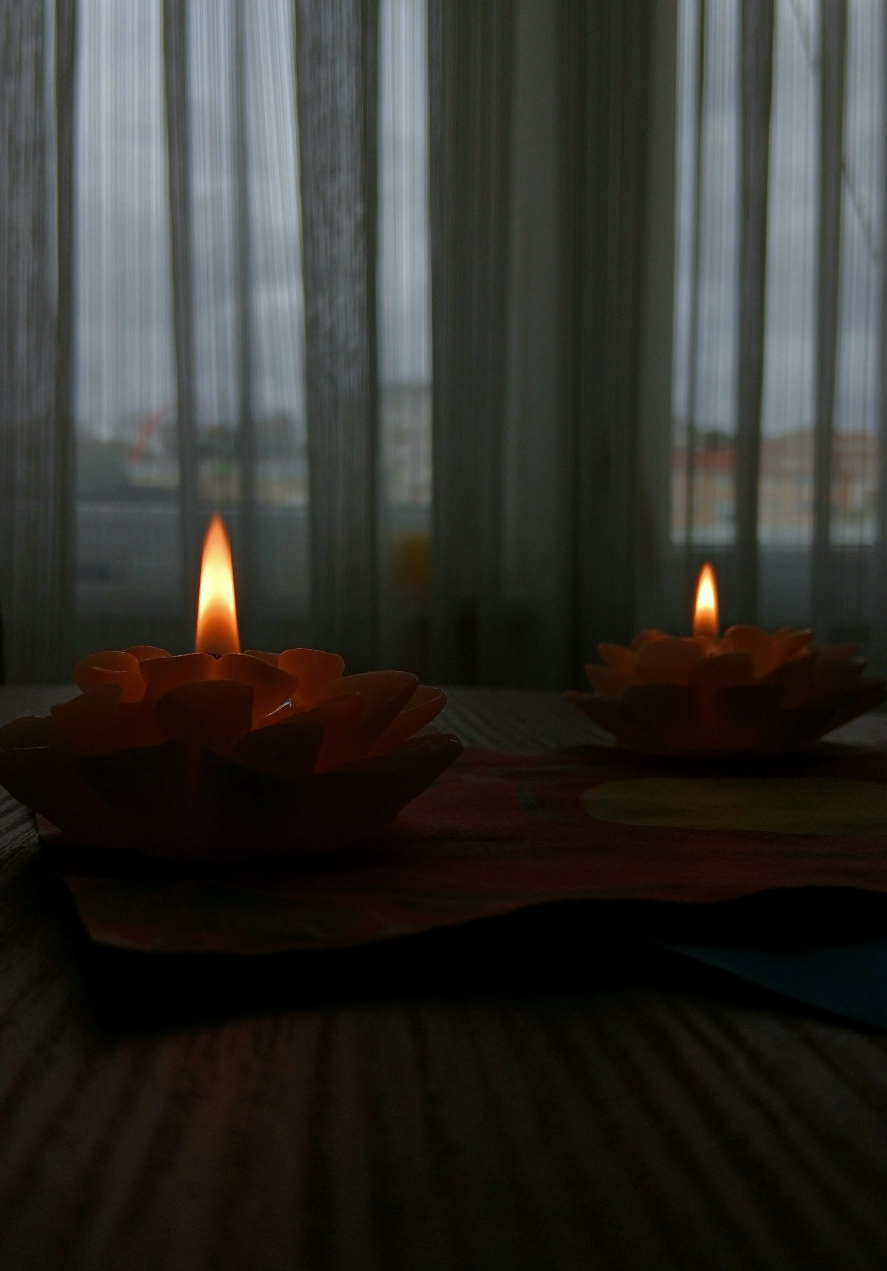 A serene image of decorative candles casting a warm glow indoors on a wooden table.