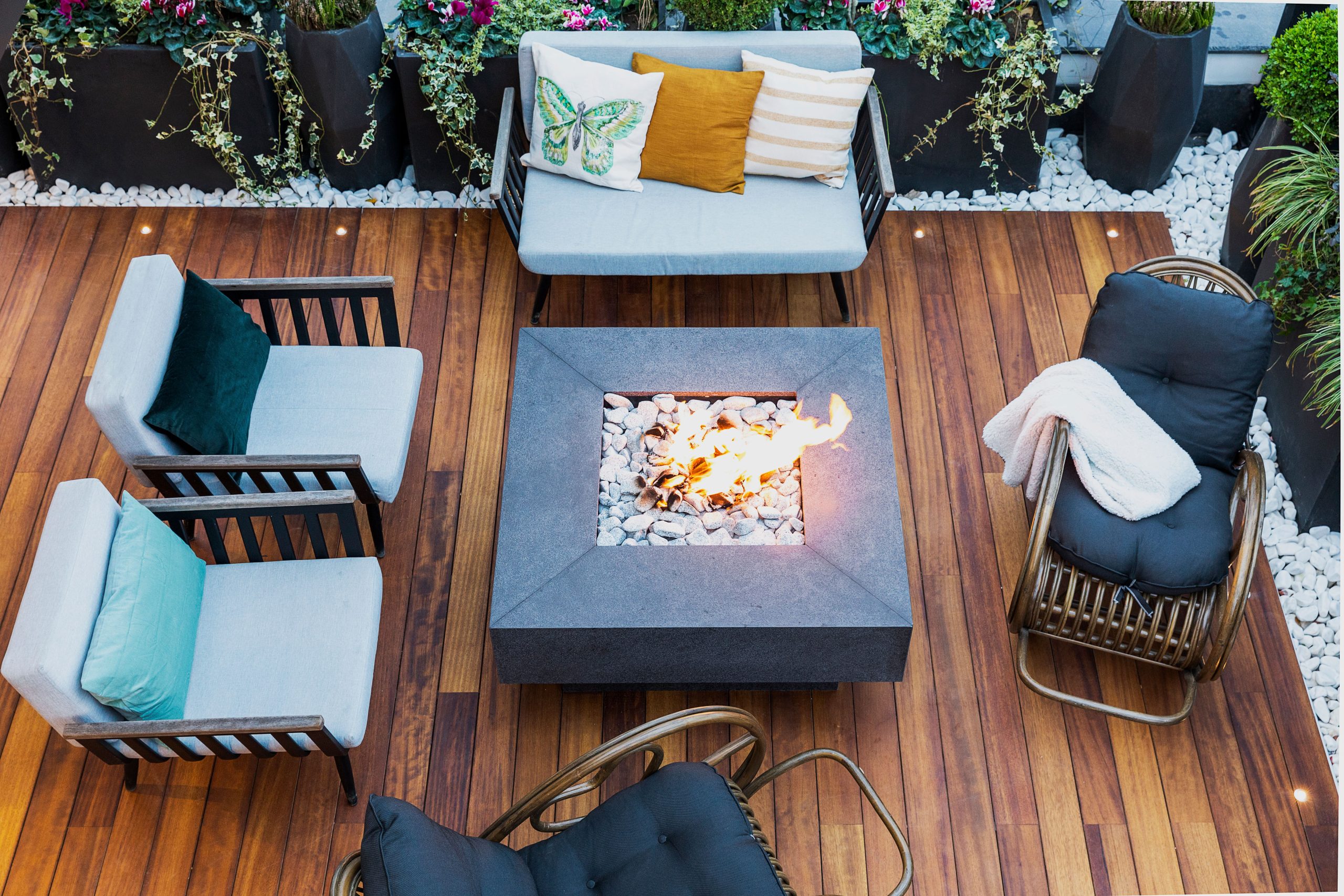 A top-down view of a modern patio featuring stylish furniture and a central firepit.