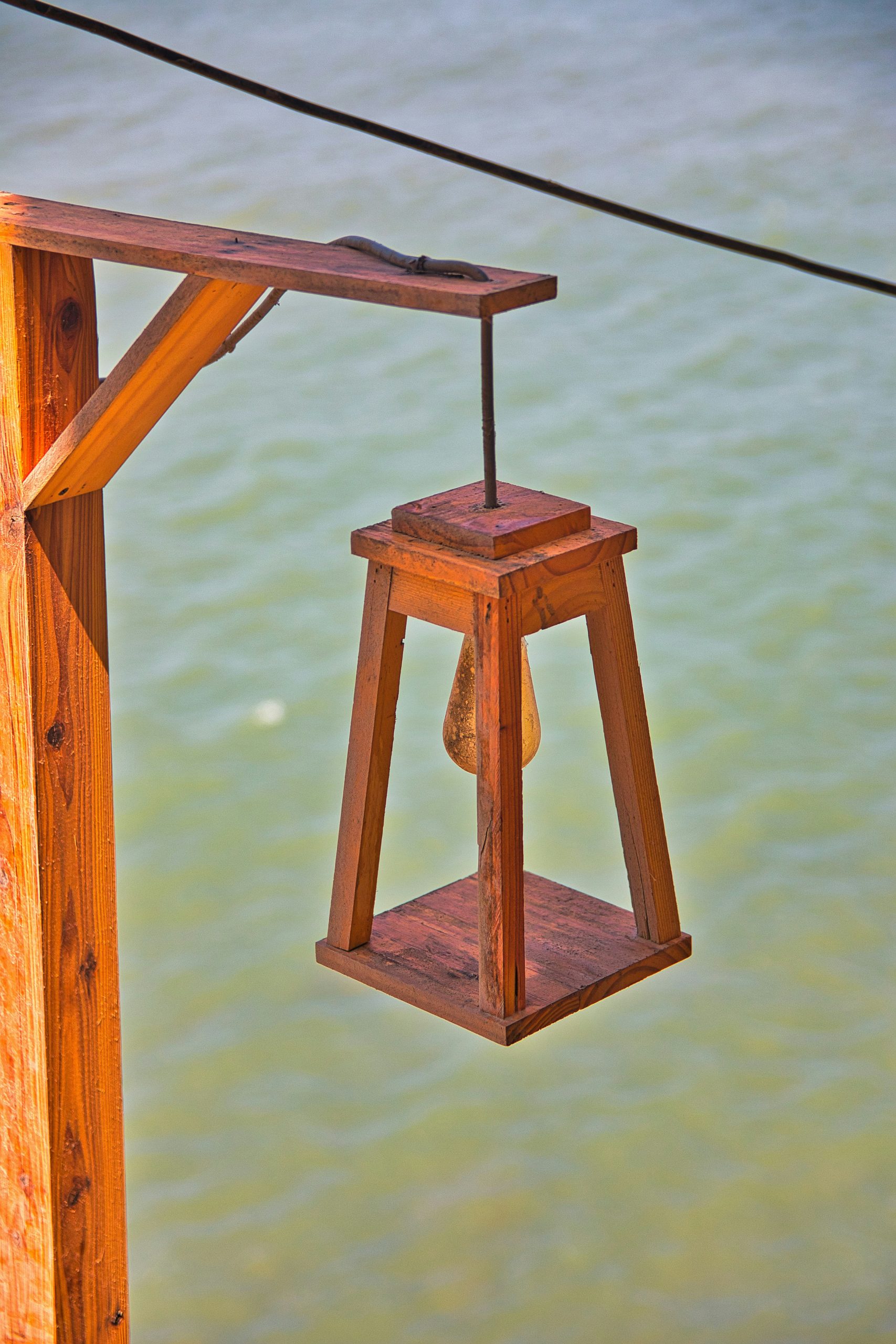 a wooden lantern hanging from a rope over a body of water