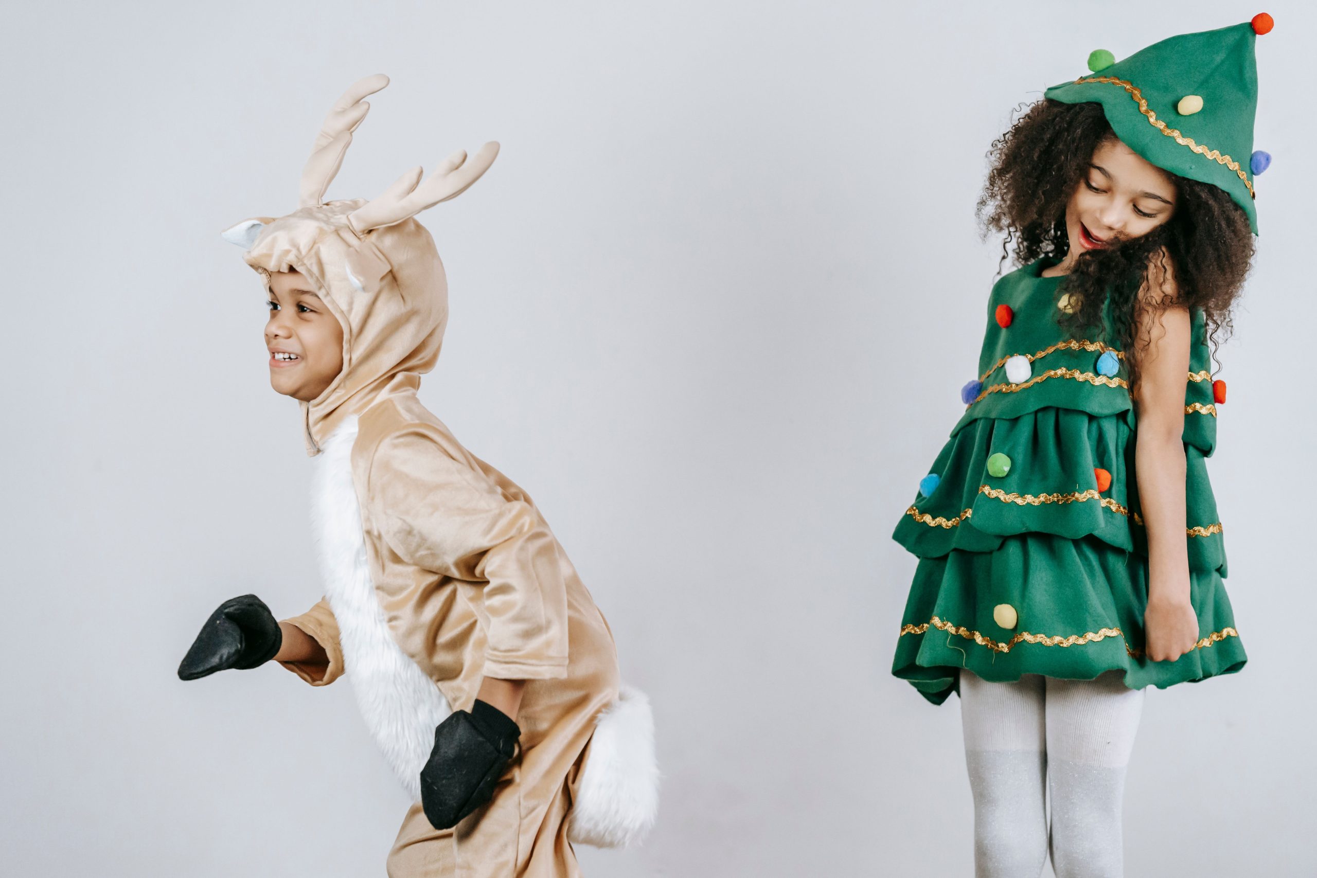 Adorable happy African American children wearing creative festive costumes playing and having fun together in light studio