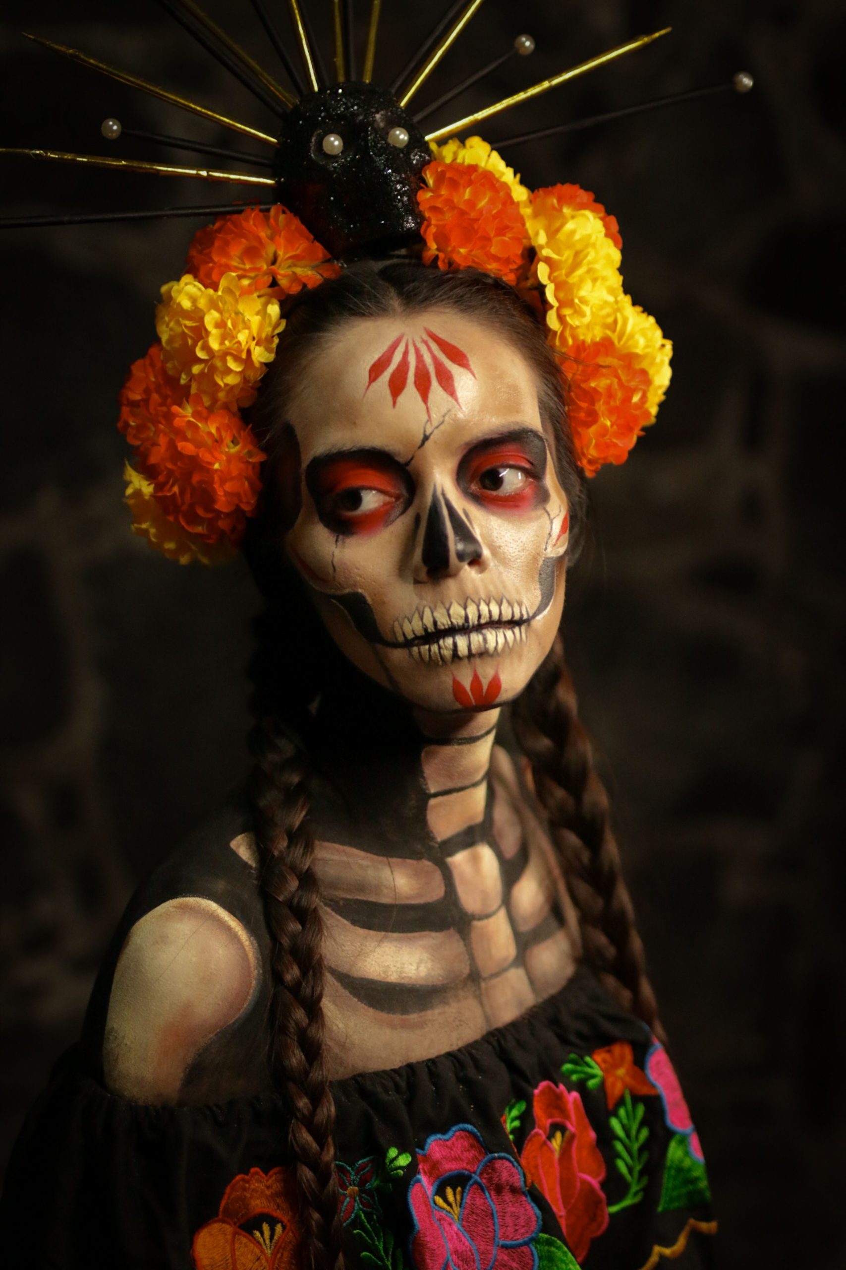 Artistic Día de los Muertos portrait with vibrant floral crown and skeletal makeup. Ideal for holiday and cultural themes.
