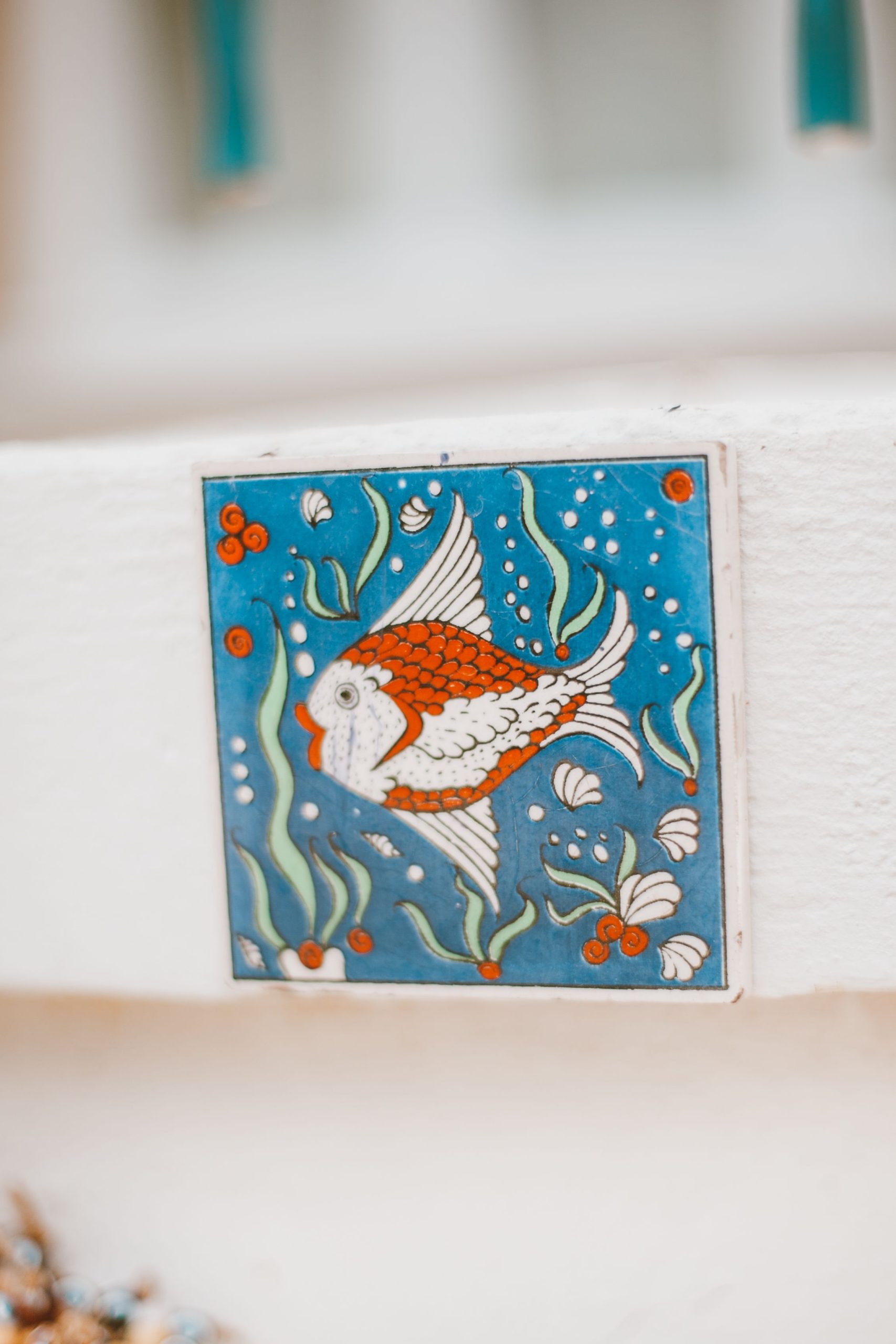 Bright and colorful fish illustrated on an ornate ceramic tile, perfect for decor.
