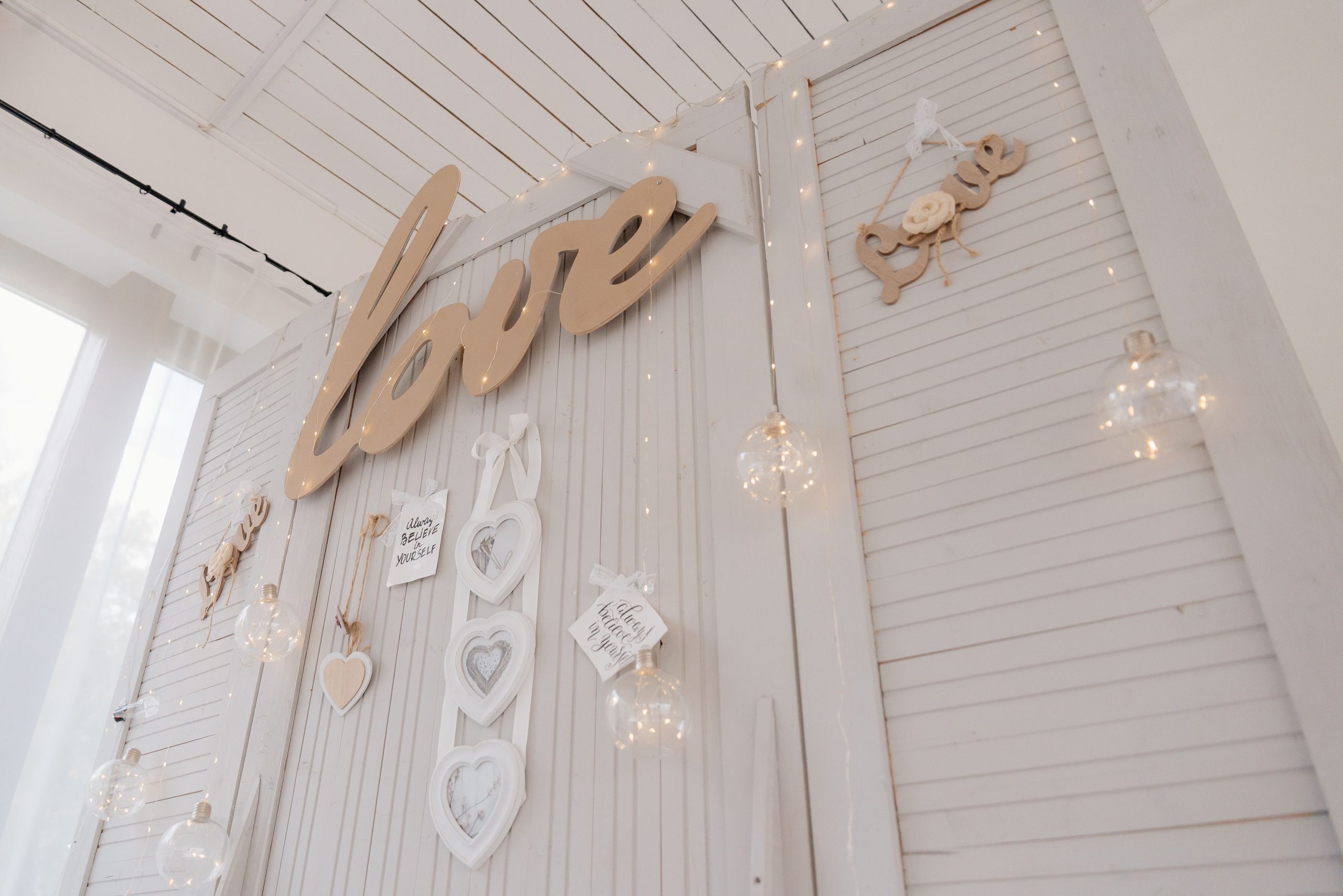 Charming white decor featuring love signs and fairy lights, perfect for romantic settings.