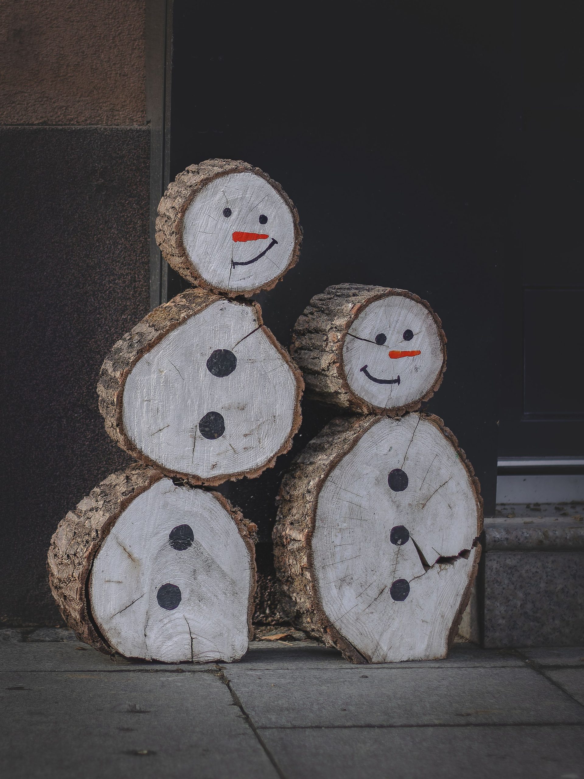 Charming wooden snowman figures crafted from logs, perfect for winter decor.