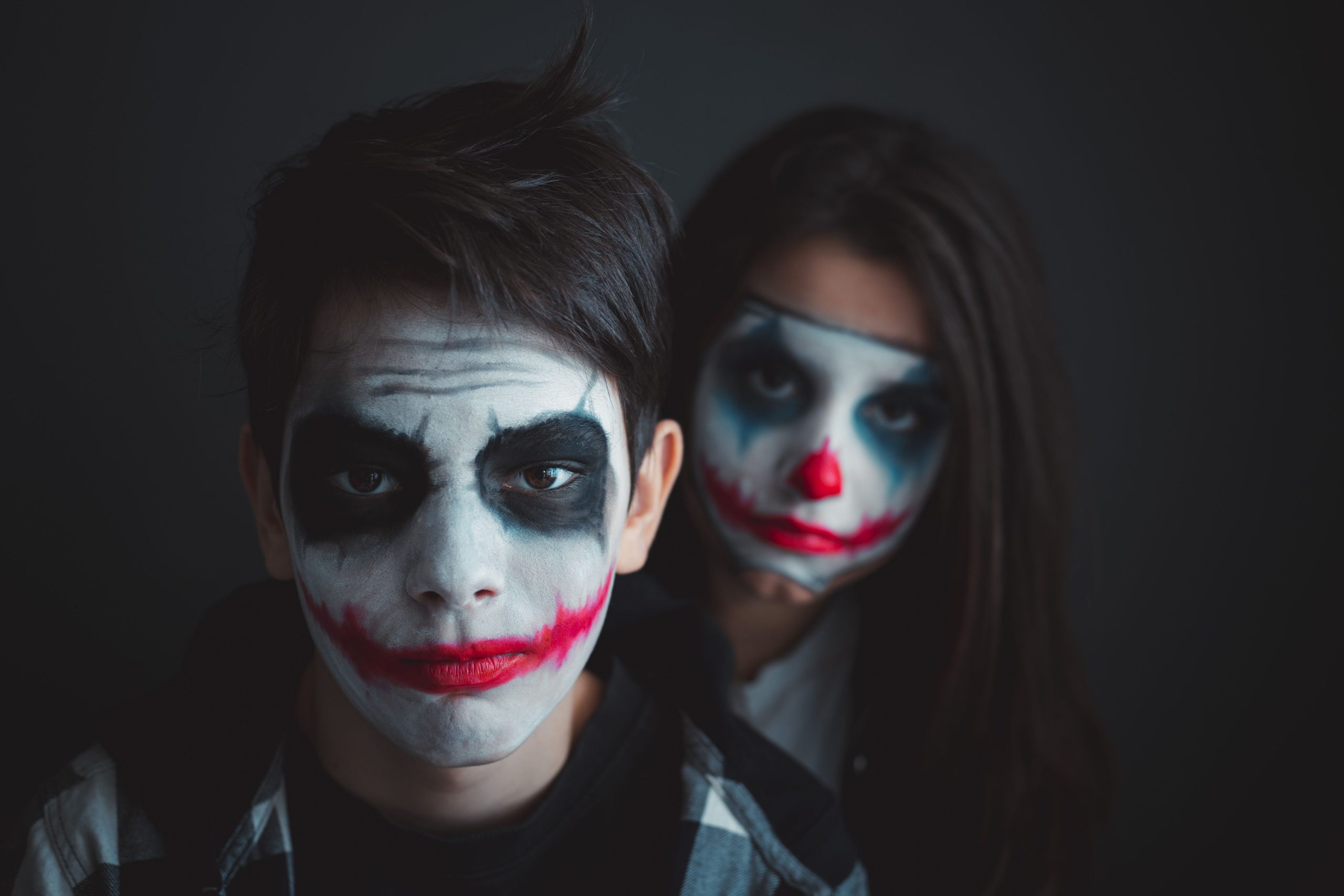 Dramatic portrait of individuals with Joker-inspired face paint, perfect for Halloween themes.
