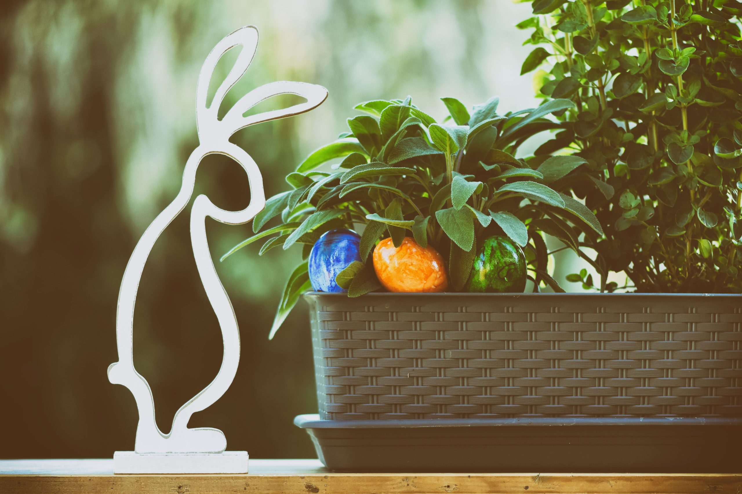 Easter-themed decor with a bunny figure, vibrant eggs, and lush plants.