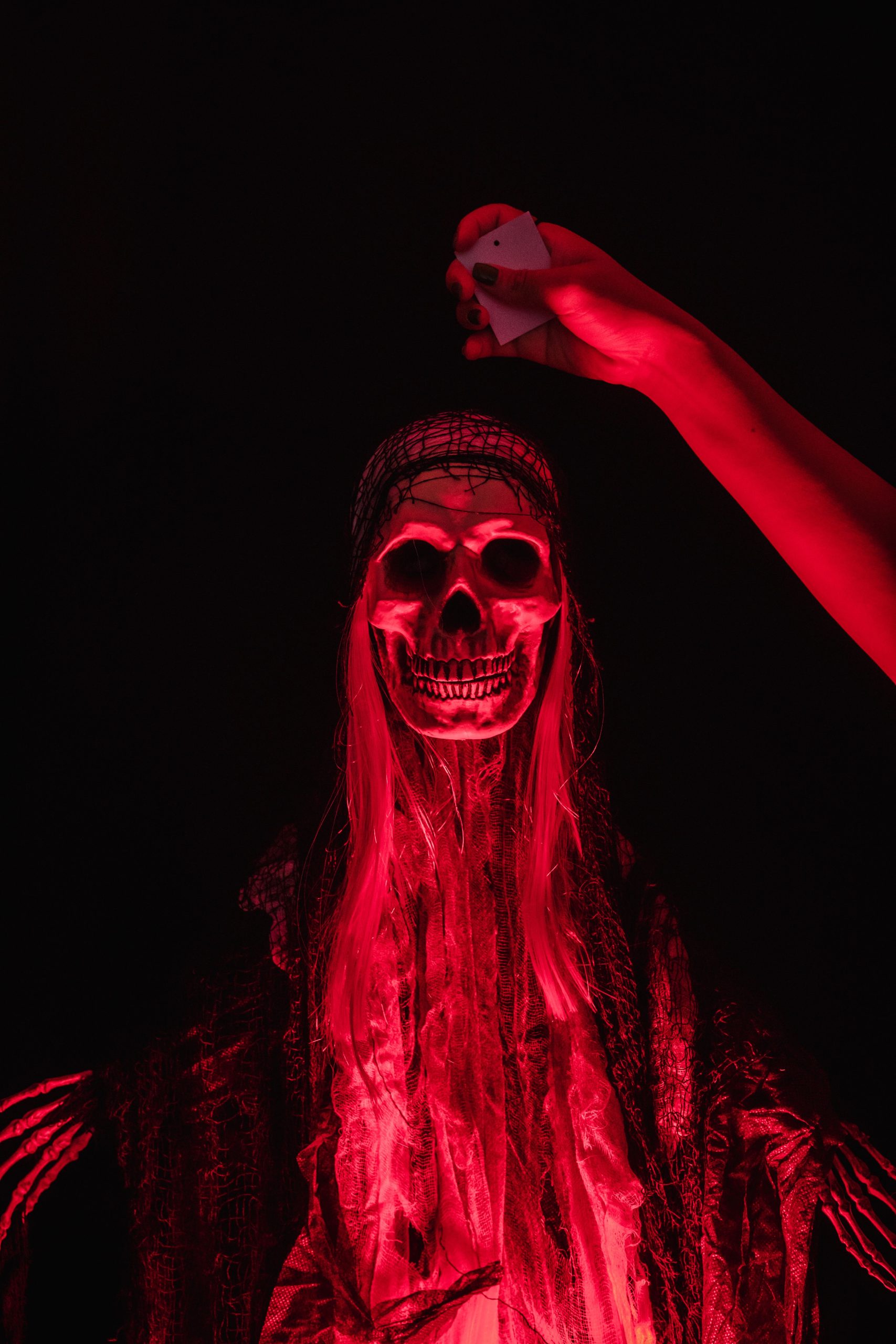 Eerie red-illuminated skeleton with human hand, perfect for Halloween decorations.