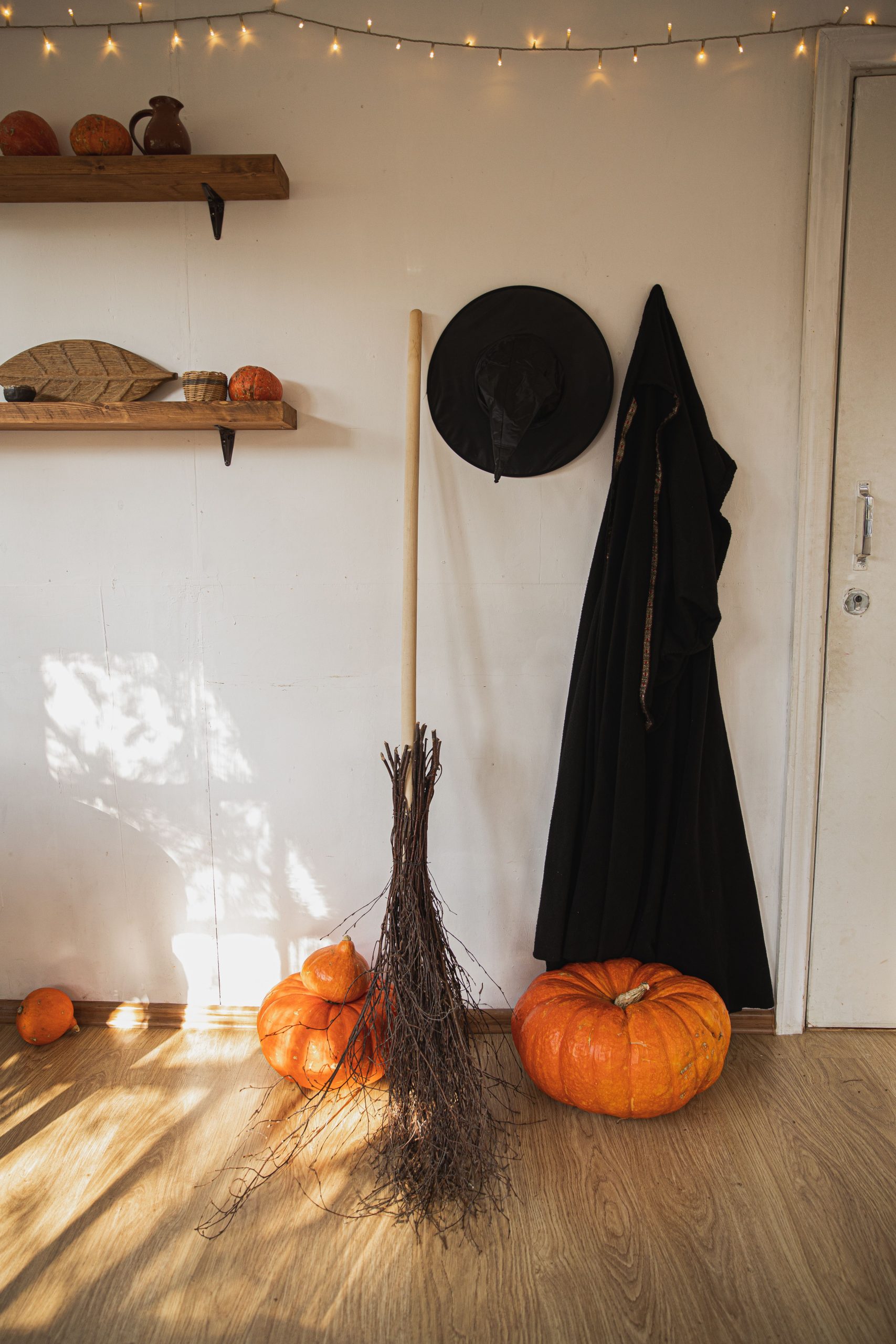 Festive Halloween setup with pumpkins, witch's hat, and broom indoors.