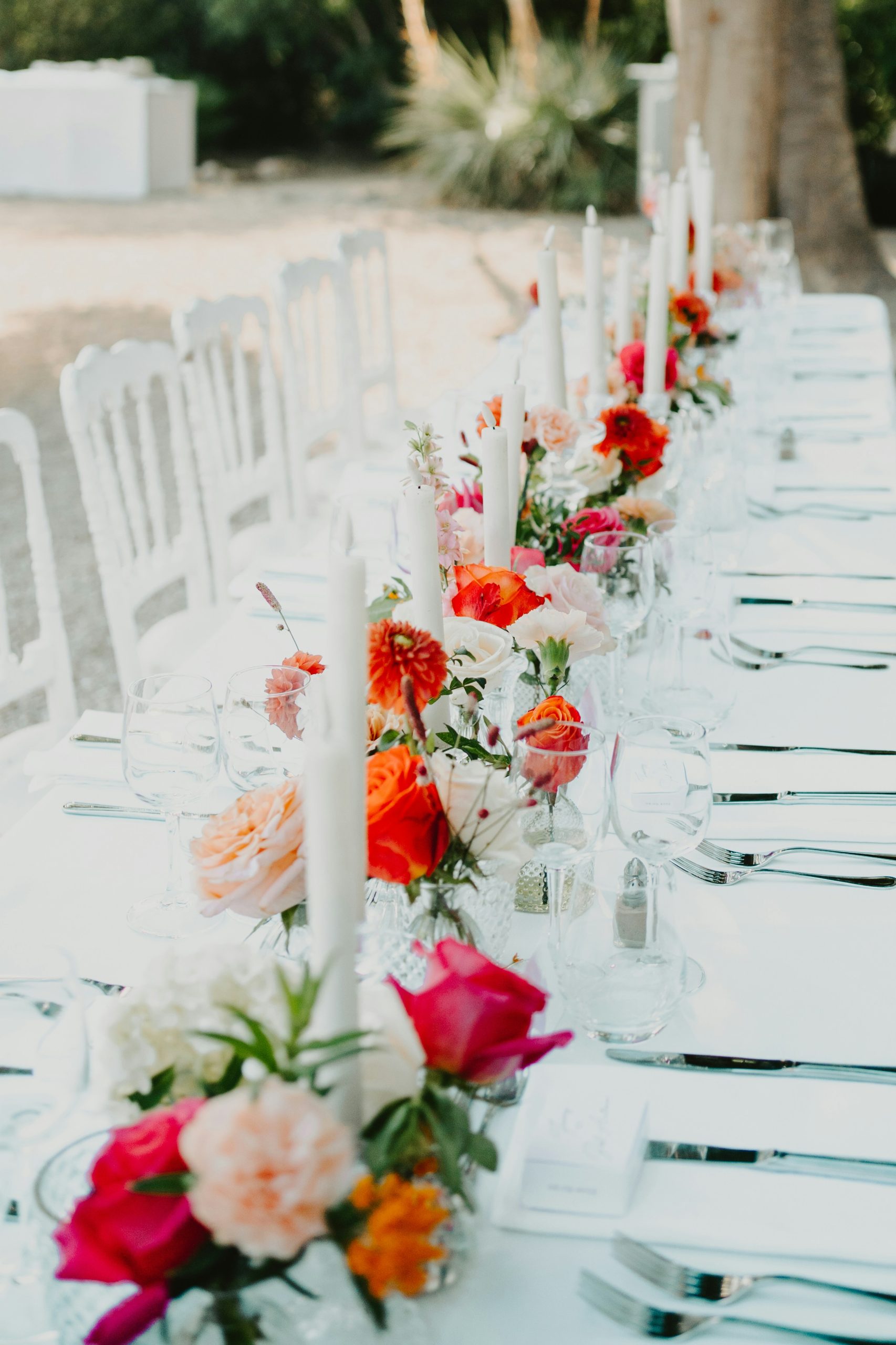 Long table adorned with colorful flowers and white candles
