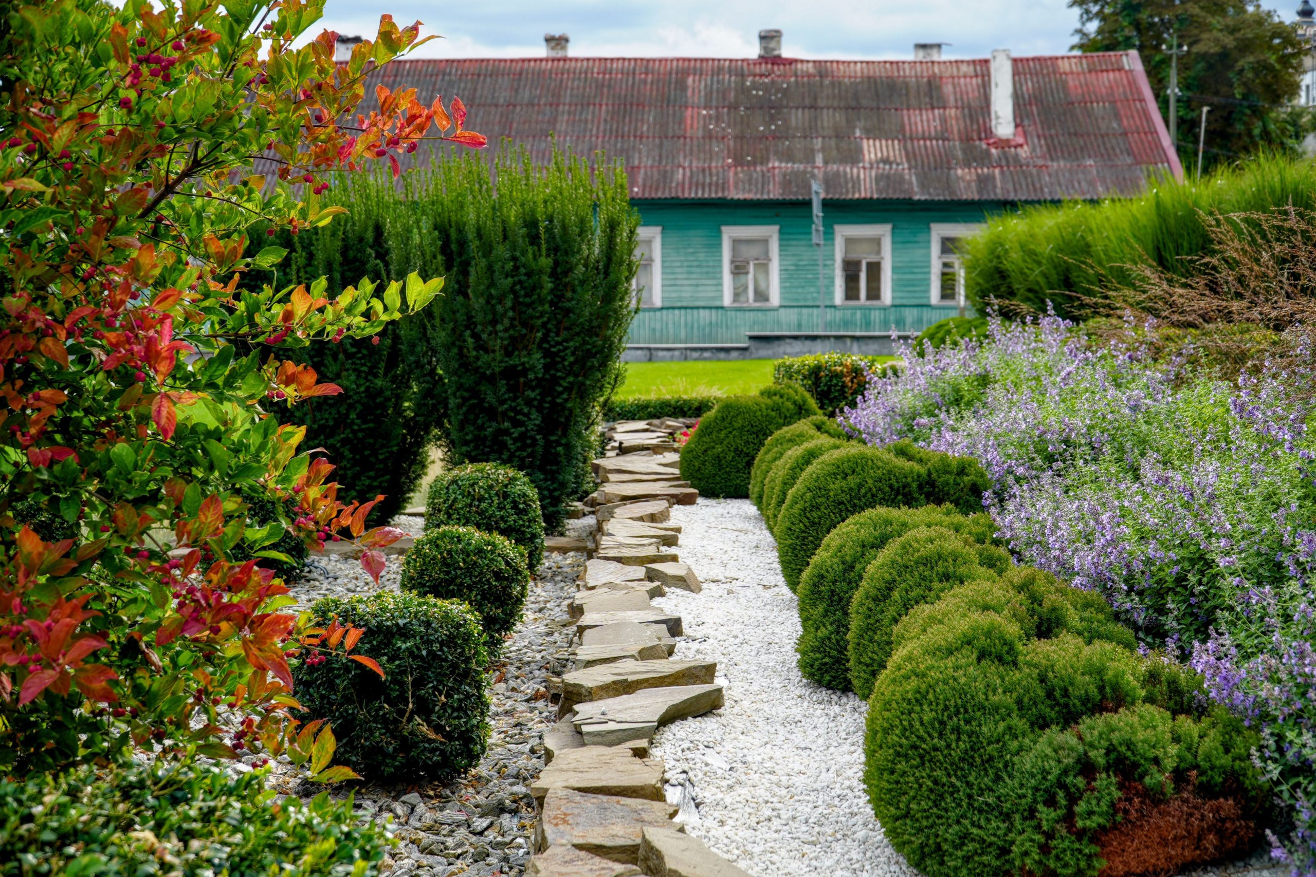 Lush garden with vibrant plants and a rustic house in Pinsk, Belarus.