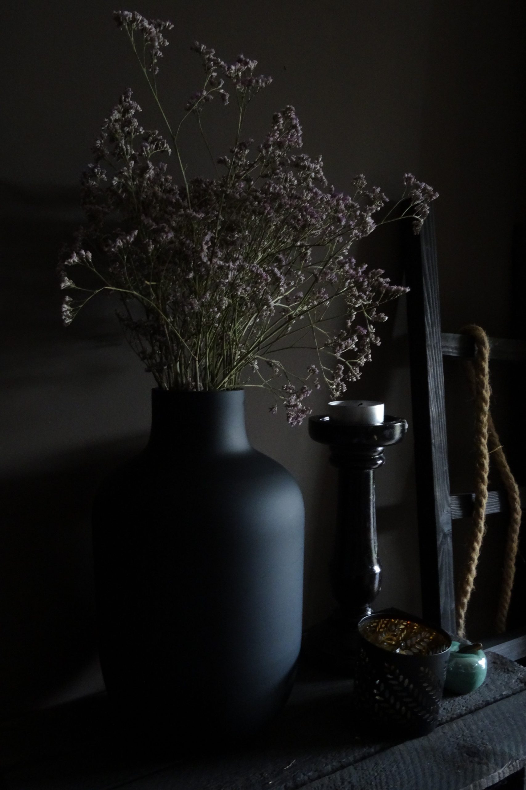 Moody interior shot featuring a dark vase with dried flowers, perfect for stylish home decor.