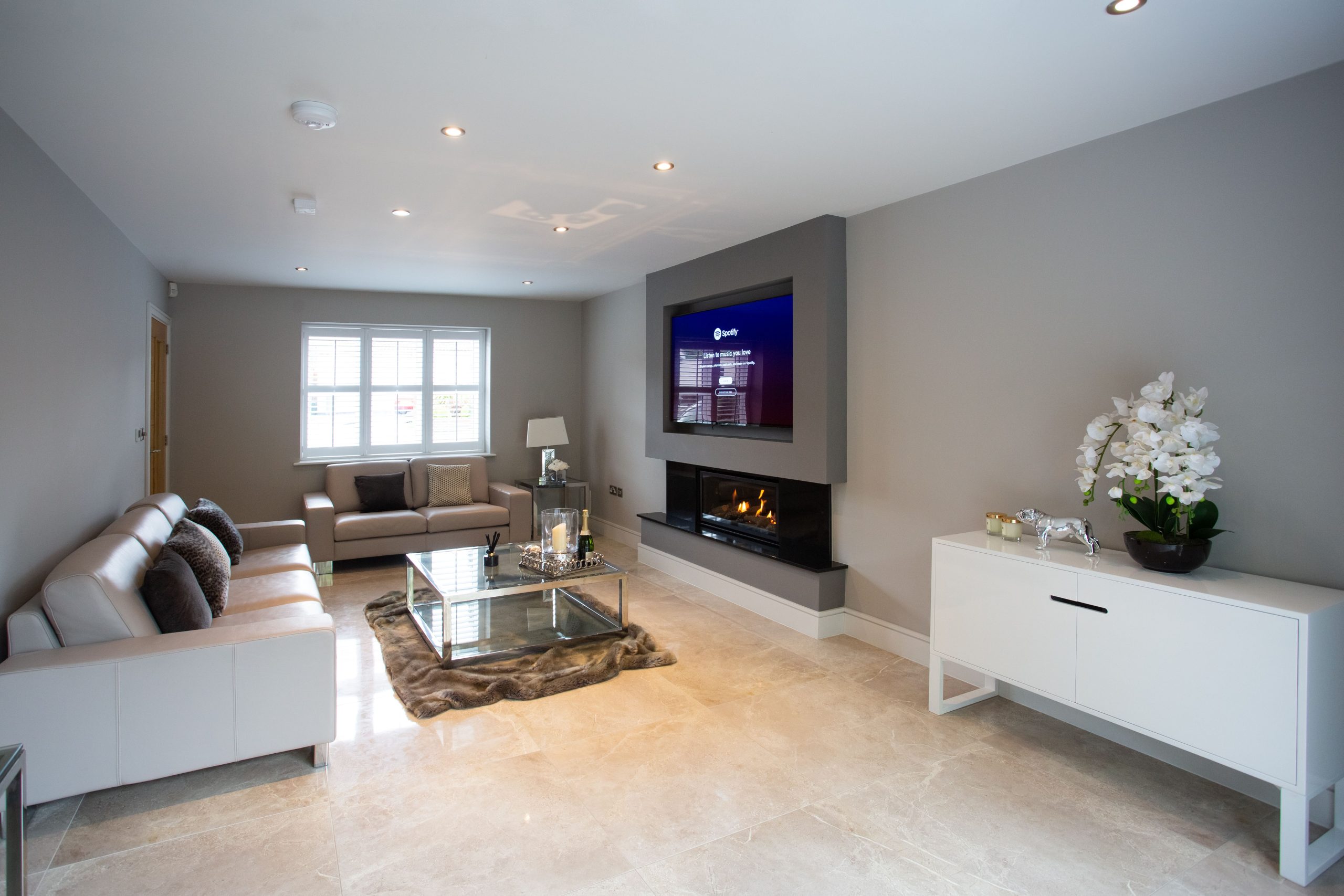 Spacious and elegant modern living room featuring a cozy fireplace and stylish decor.
