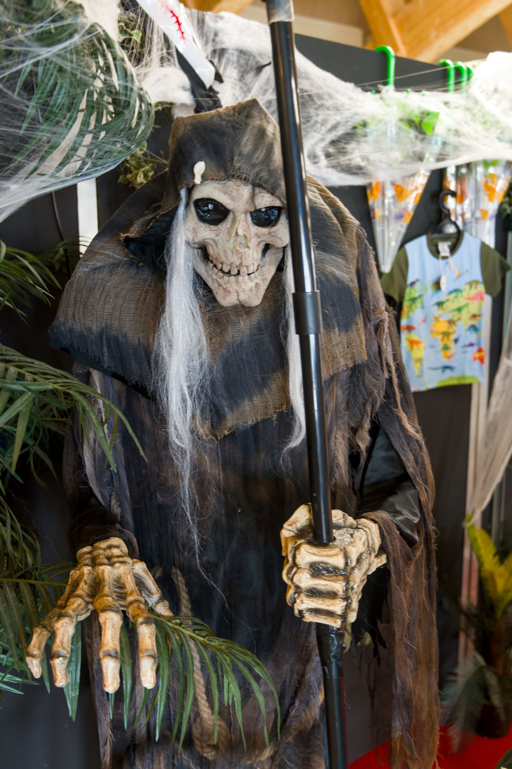 Spooky Grim Reaper decoration with cobwebs and skeleton features for Halloween ambiance.