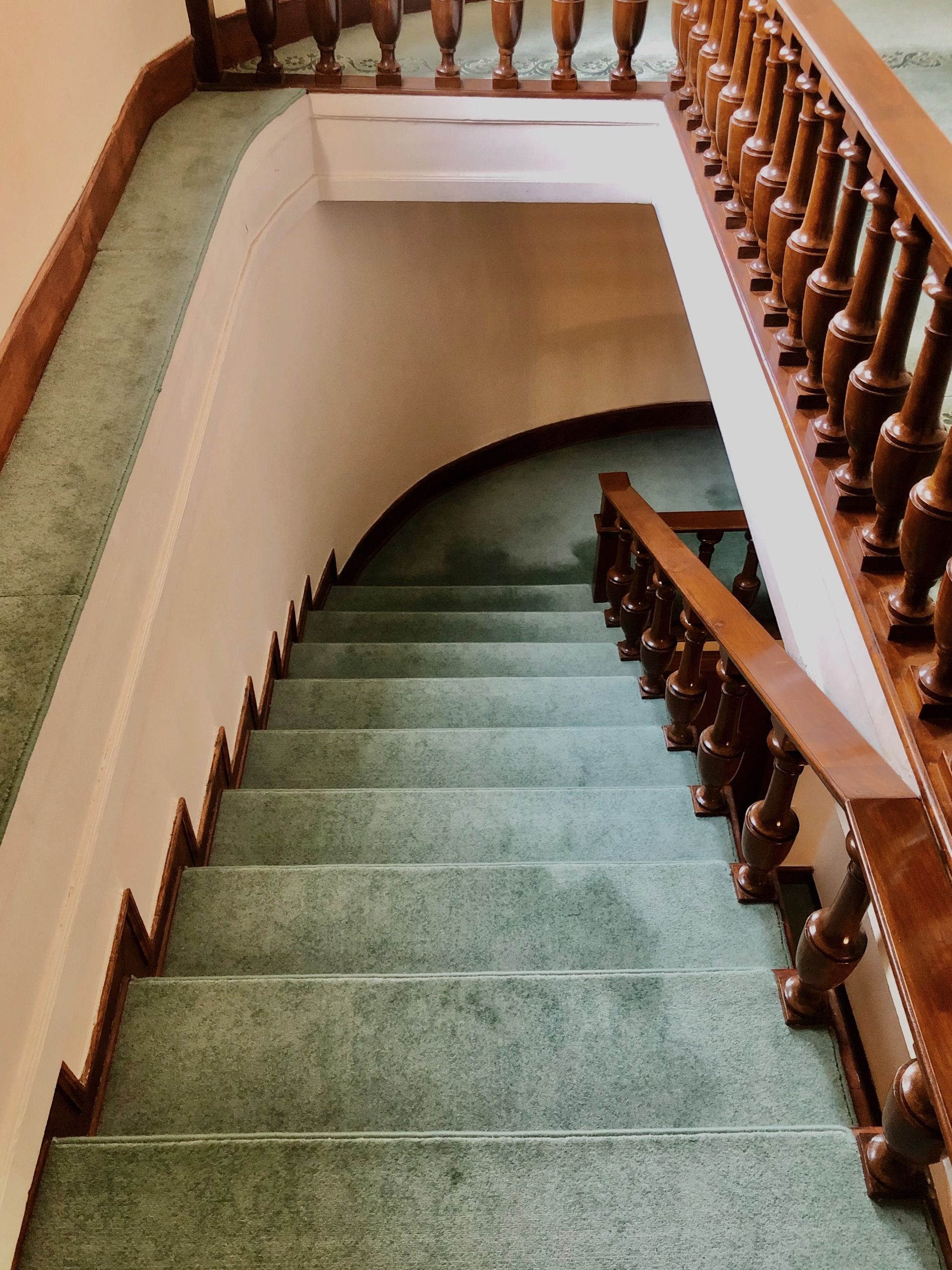 Top view of a classic carpeted staircase with wooden railing indoors.