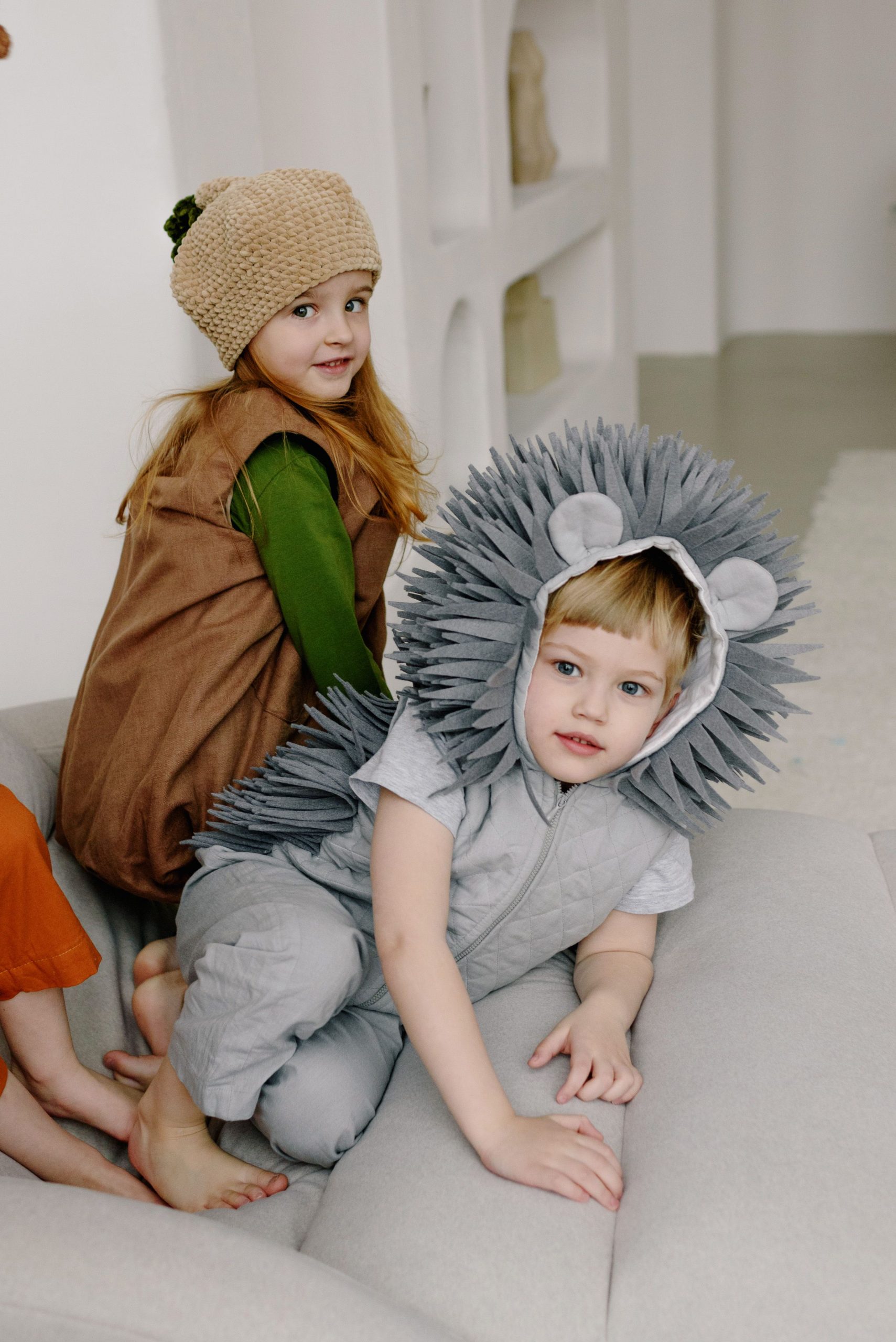 Two children dressed in adorable animal and nature-themed costumes having fun indoors.