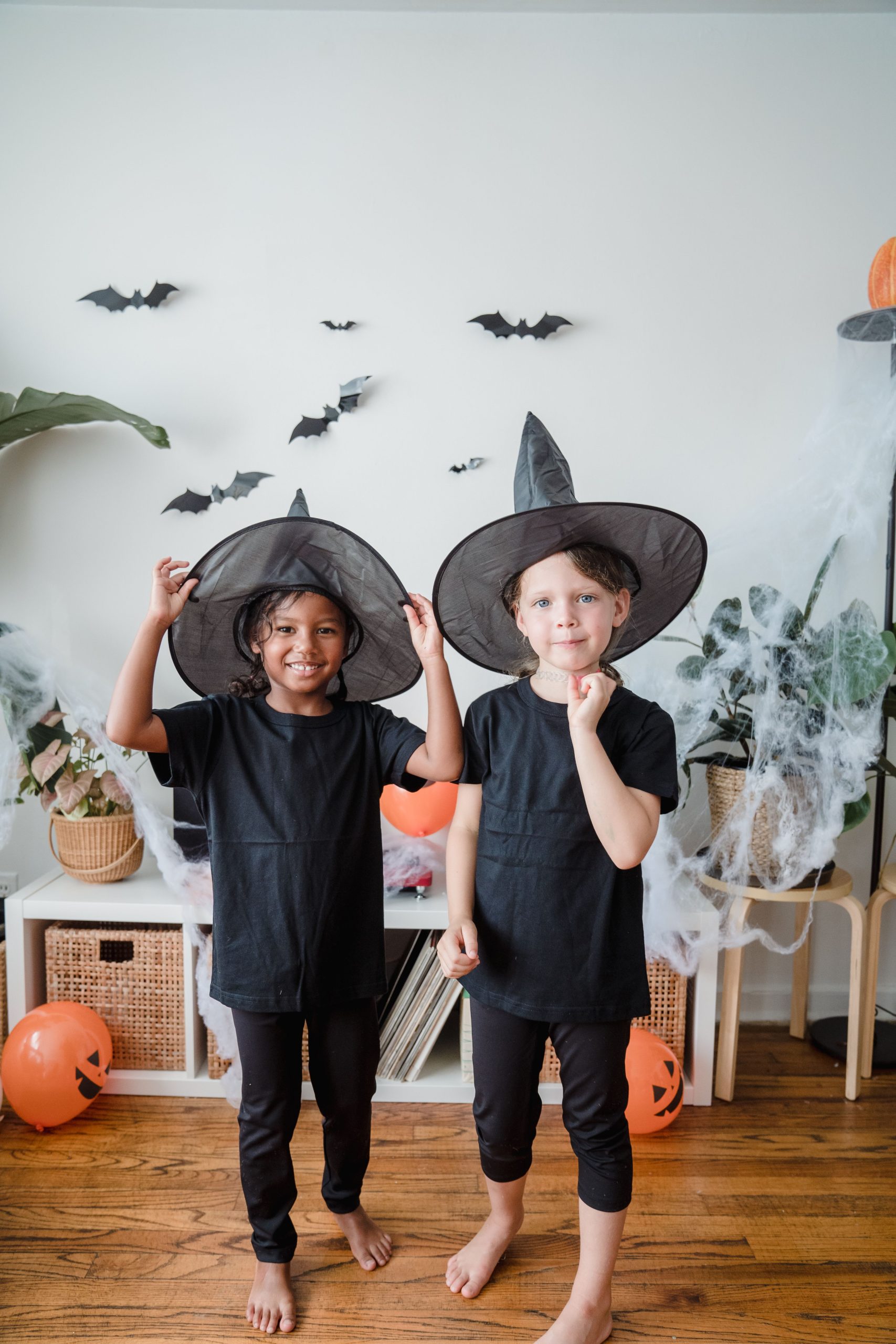 Two kids in witch costumes enjoying a Halloween indoor celebration with decorations.