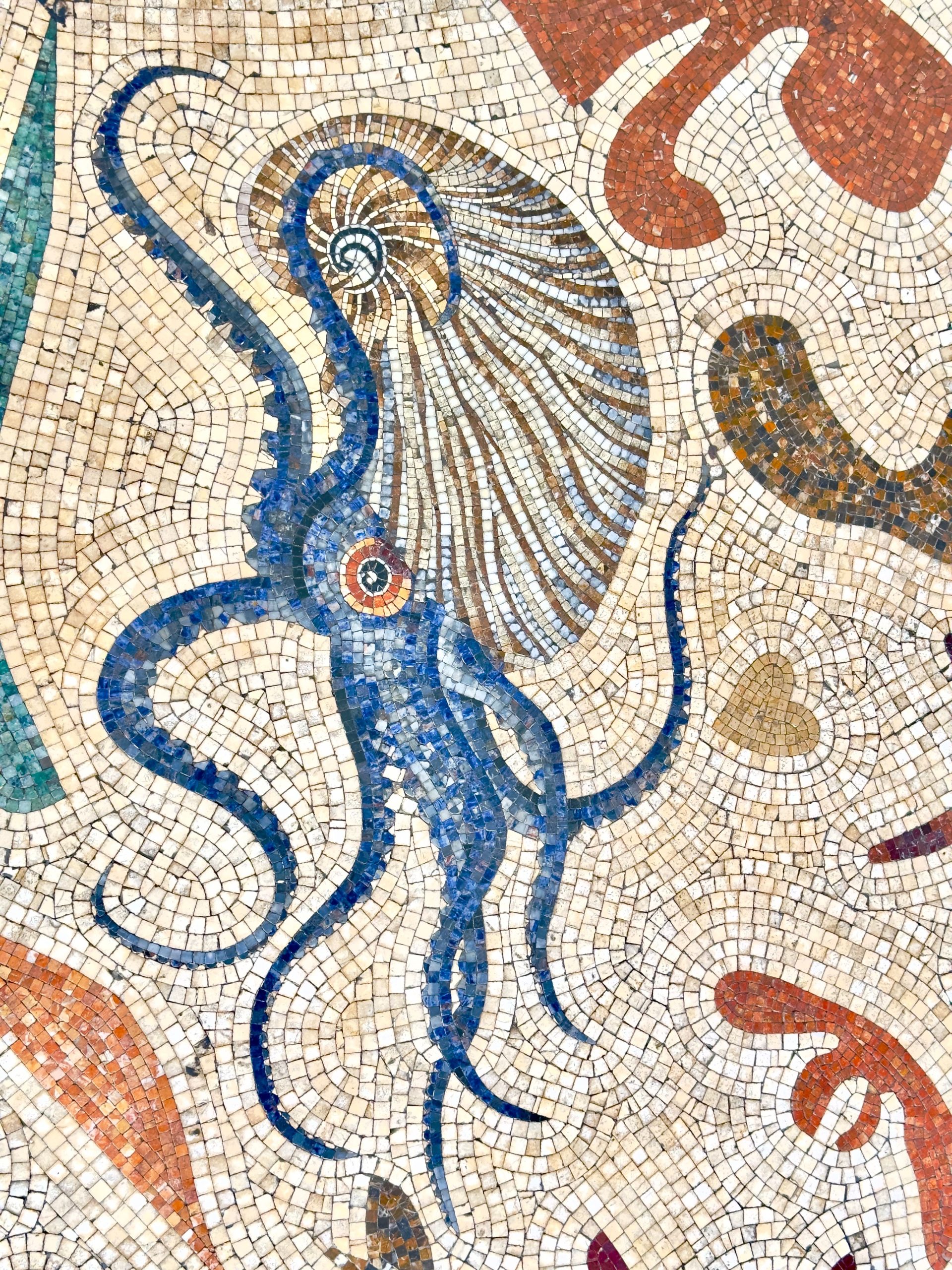 Vibrant mosaic tile art depicting a blue octopus, showcasing ancient Roman style.