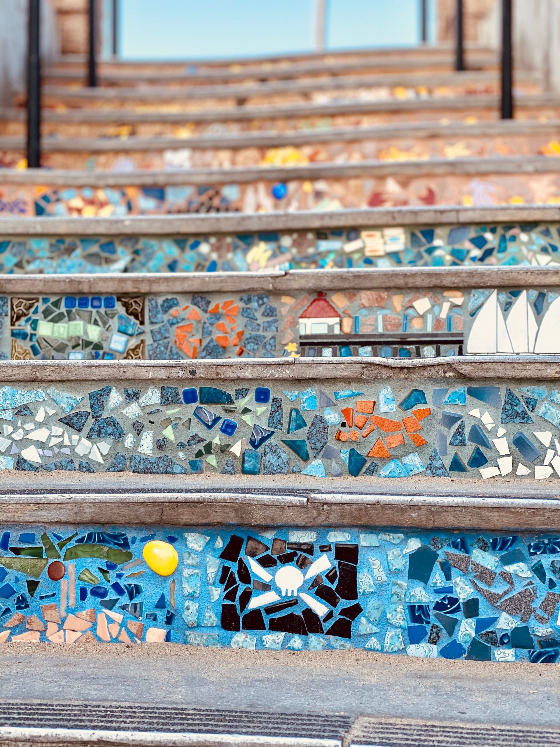 Vibrant mosaic tiles embellish an outdoor staircase, creating a lively art installation.