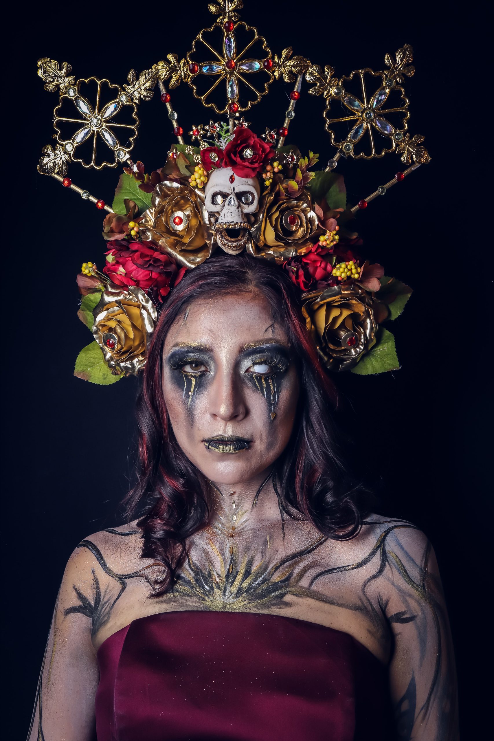 Vivid portrait of a woman in Halloween costume with floral skull headpiece and dramatic makeup.