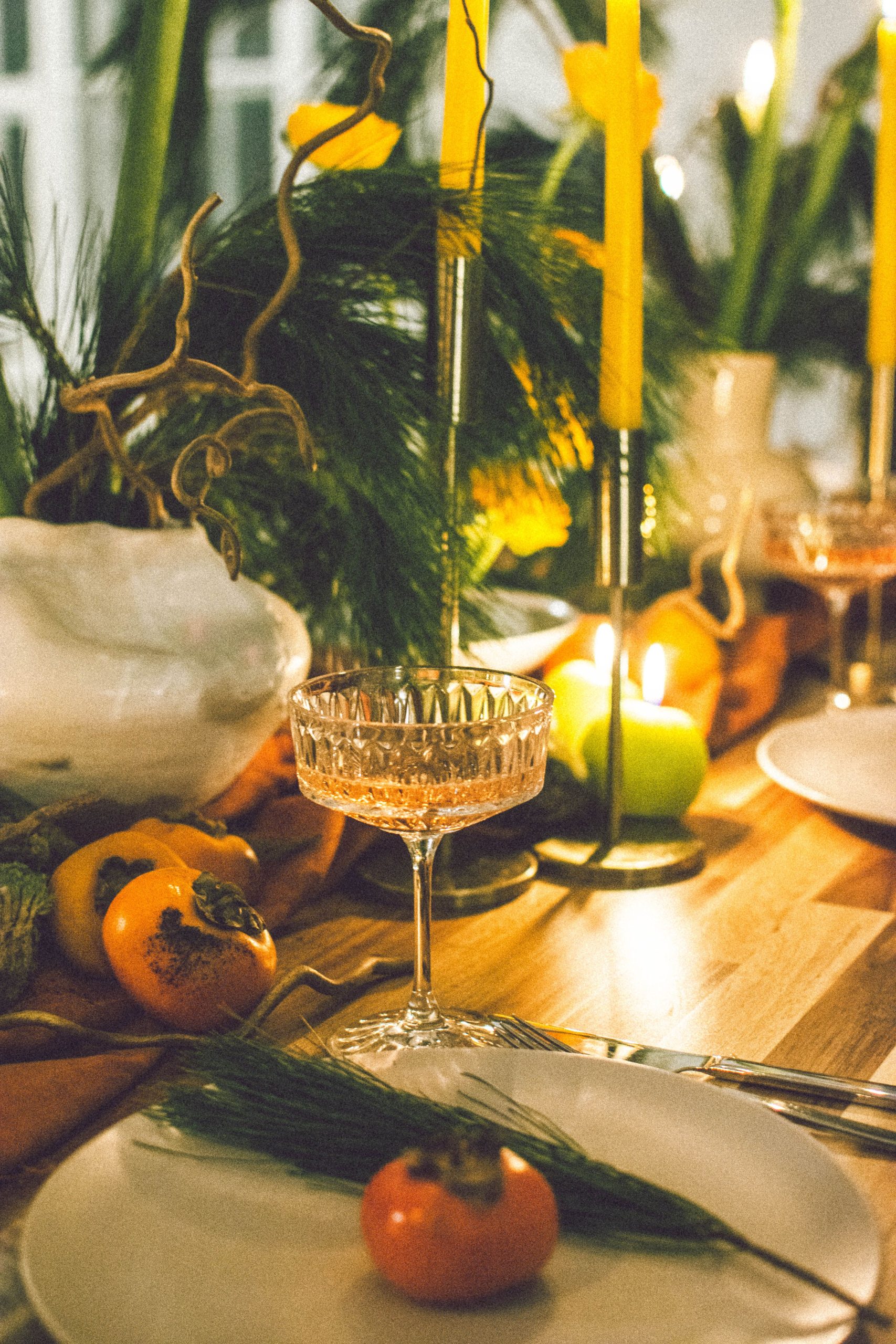 Warm and cozy autumn dining table with candles, fruits, and elegant glassware for a festive dinner vibe.